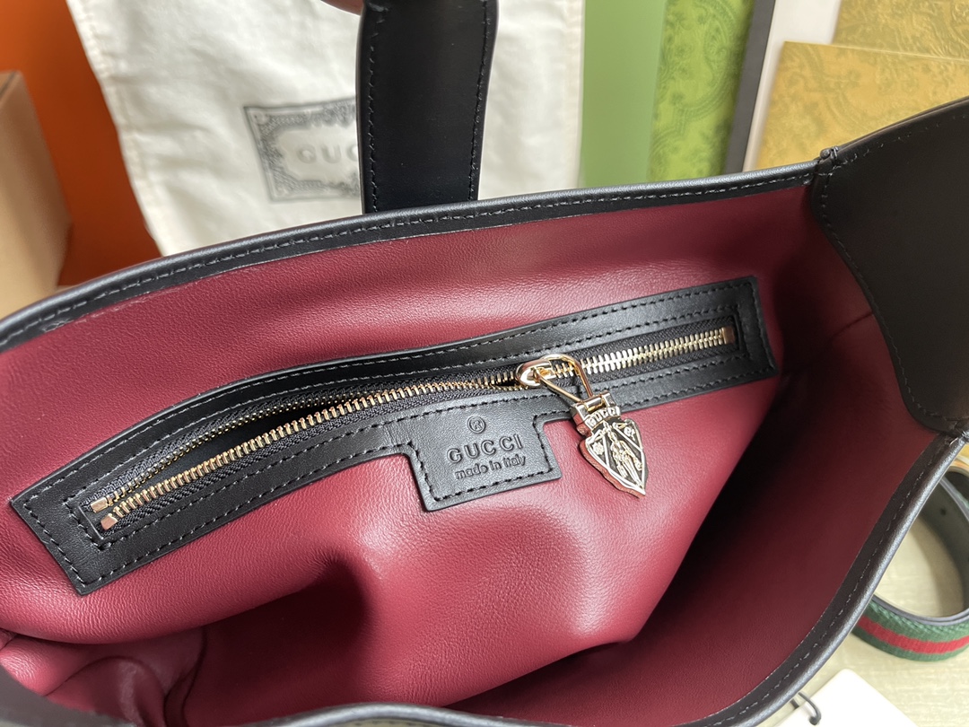 Modelo: 782849 Tamanho: 27.5/19/4 P1900 Esta nova bolsa de ombro Gucci Jackie é confeccionada com couros da melhor qualidade e mostra a habilidade artesanal, a forma crescente e o design elegante das icônicas bolsas de ombro da marca. A combinação de ferragens douradas, debrum de couro e alças listradas adicionais traz mais possibilidades de uso para a bolsa de ombro Gucci Jackie, que vem em um pequeno couro sintético preto. A combinação de pele preta, ferragens em tom dourado claro, debrum em pele e alças adicionais às riscas confere ainda mais versatilidade a esta pequena mala de ombro da coleção Gucci Jackie.Pele pretaCouro em tom dourado claroRevestimento em peleInterior: um bolso com fecho de correr com emblema GucciPuxadores com fecho de correr (18 cm de altura)Alça de ombro amovível em tecido (52 cm de altura)Fecho com gancho e argolaFábricas de alto impacto