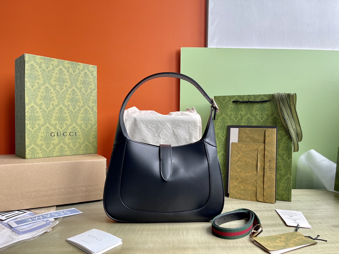 Modelo: 782849 Talla: 27.5/19/4 P1900 Este nuevo bolso bandolera Gucci Jackie está confeccionado con pieles de la mejor calidad y muestra la artesanía, la forma de media luna y el elegante diseño de los icónicos bolsos bandolera de la marca. La combinación de herrajes en tono dorado, ribetes de piel y correas adicionales a rayas aporta más posibilidades de uso al bolso bandolera Gucci Jackie, que se presenta en un tamaño pequeño en polipiel negra. La combinación de piel negra, herrajes en tono dorado claro, ribetes de piel y correas adicionales a rayas confiere aún más versatilidad a este bolso bandolera pequeño de la colección Gucci Jackie.Piel negraPiel en tono dorado claroForro de pielInterior: un bolsillo con cremallera con insignia GucciAsas superiores con cremallera (18 cm de altura)Correa bandolera de cincha extraíble (52 cm de altura)Cierre de gancho y lazo-Fábricas de alto impacto