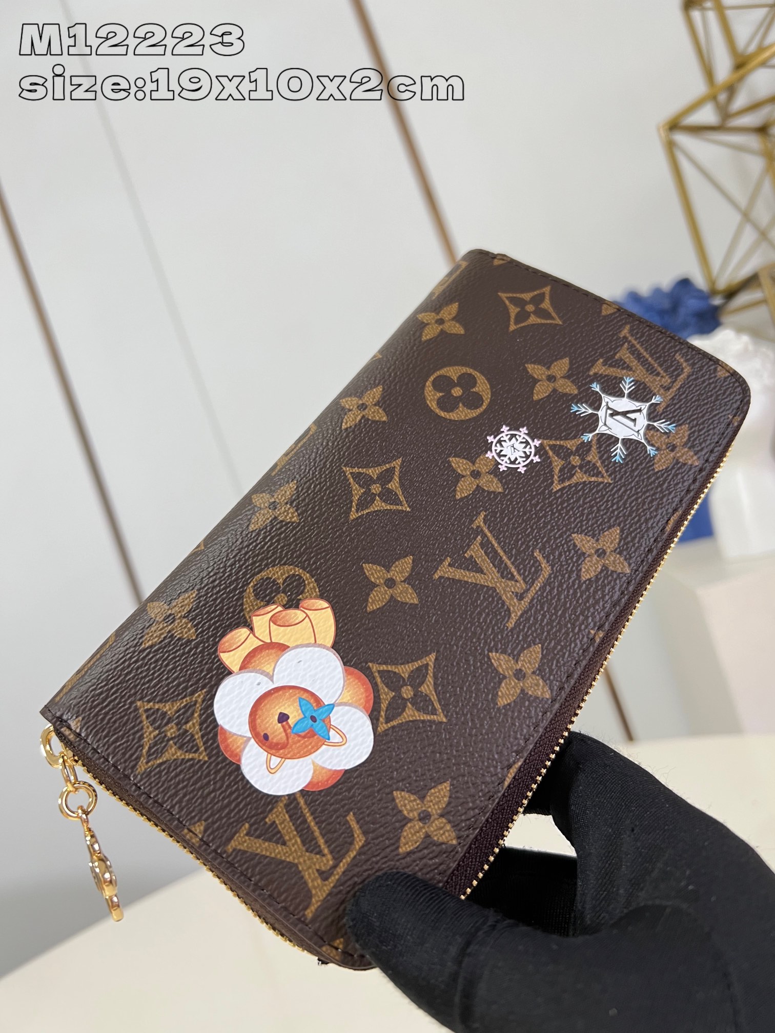 M12223 This festive zippy wallet from the Snow Show collection features Louis Vuitton's Vivienne mascot skiing in the LV snowflakes. Crafted in the iconic Monogram canvas and lined in Azur Frost leather, this playful design comes with multiple interior pockets, three compartments, and twelve business card slots 19.5 x 10.5 cm (L x H x W). x 2.5 cm (L x H x W)