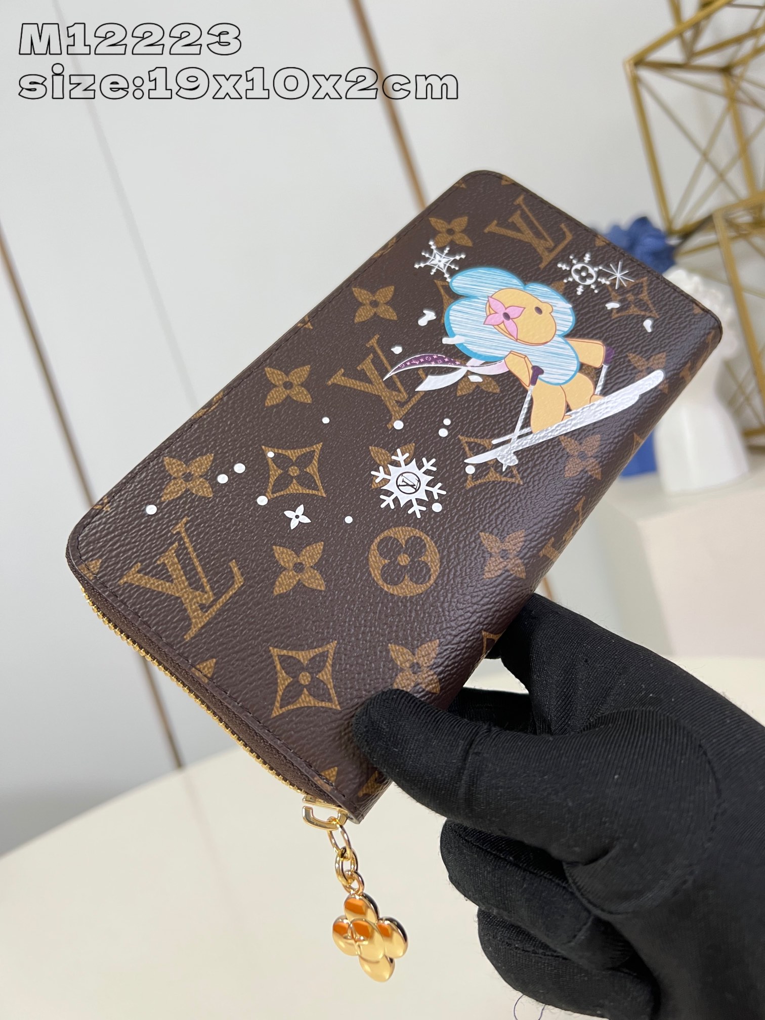 M12223 This festive zippy wallet from the Snow Show collection features Louis Vuitton's Vivienne mascot skiing in the LV snowflakes. Crafted in the iconic Monogram canvas and lined in Azur Frost leather, this playful design comes with multiple interior pockets, three compartments, and twelve business card slots 19.5 x 10.5 cm (L x H x W). x 2.5 cm (L x H x W)