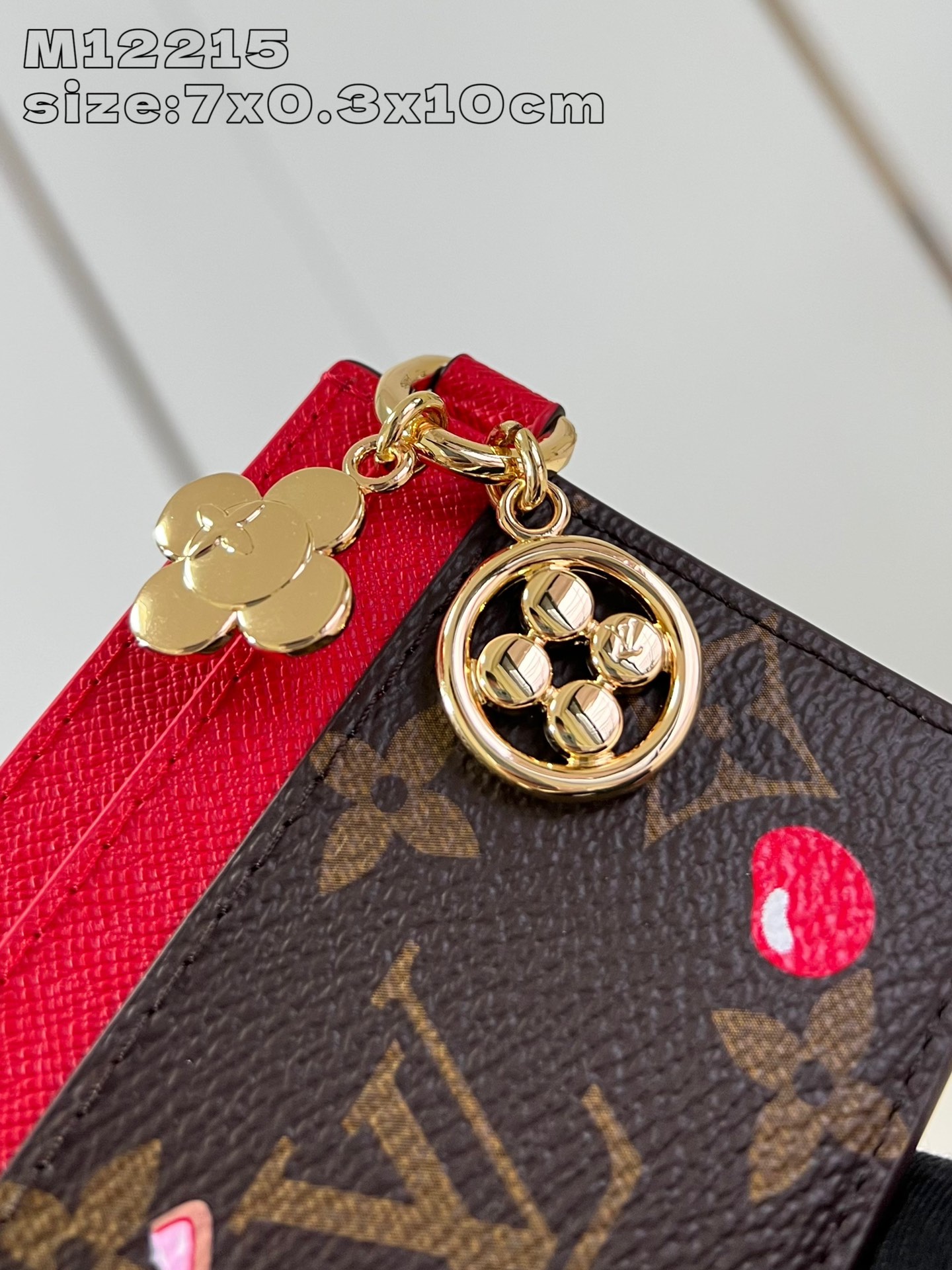 M12215 This LV Charms card holder from the Candy Factory collection invites the brand's mascot to celebrate the holiday season with a Monogram canvas depicting Vivienne wandering through a joyful landscape of candy Vivienne stylized embellishments and LV floral detailing 7.3 x 0.3 x 10.2 cm (H x W x L).