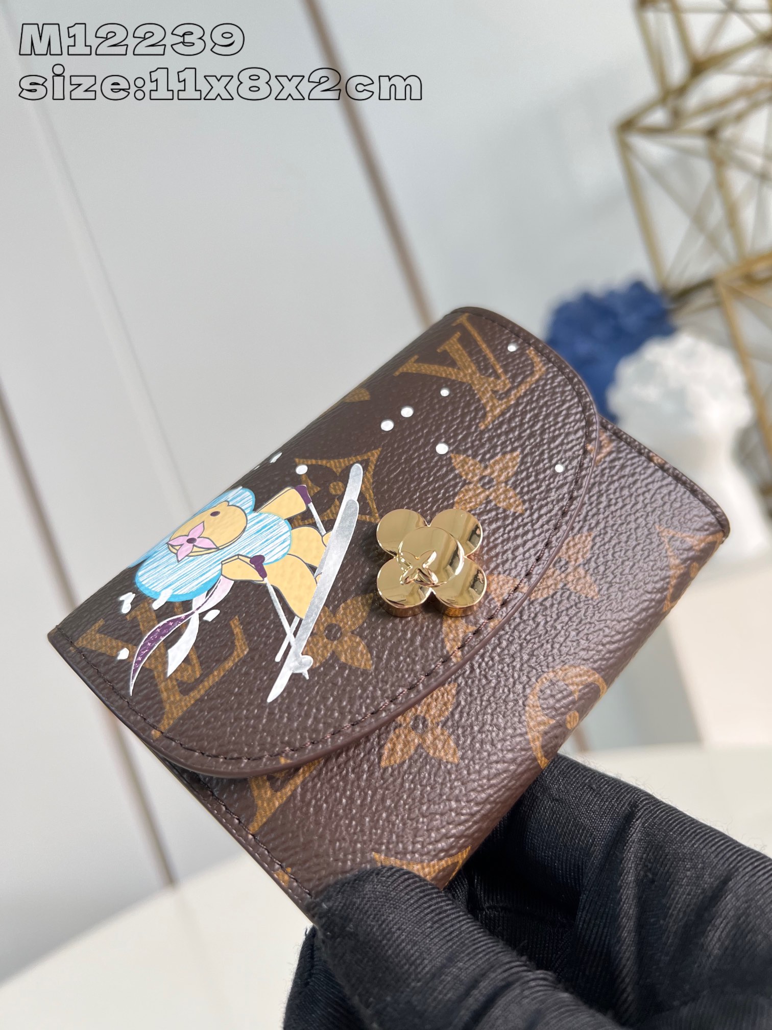 M12239 The Rosalie coin purse from the Snow Show collection is revived for this festive season with a playful and personalized design embellished with a vibrant illustration of the brand's iconic mascot, Vivienne, skiing with the adorable polar bears amidst the snowflakes of the LV. This compact coin purse is made of classic Monogram canvas with pockets for coins, banknotes and business cards. Business card with Vivienne-shaped snap closure 11 x 8 x 2.5 cm (L x H x W)