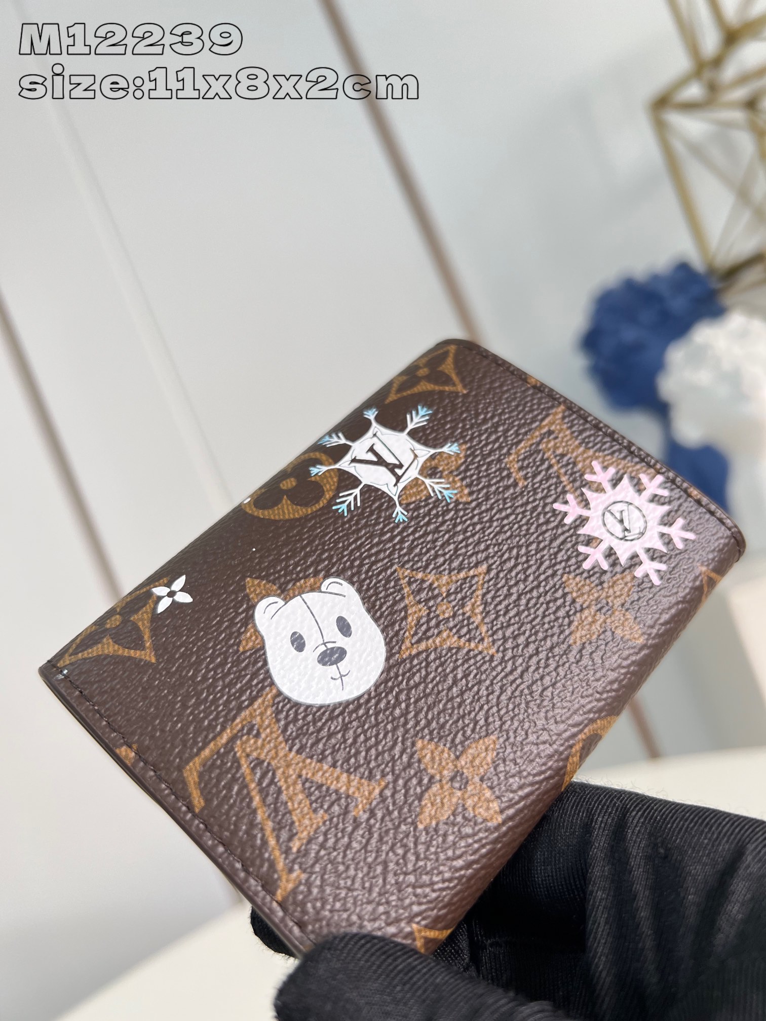 M12239 El monedero Rosalie de la colección Snow Show se revisita esta temporada festiva con un diseño lúdico y personalizado adornado con una vibrante ilustración que representa a la icónica mascota de la marca, Vivienne, esquiando con los adorables osos polares en medio de los copos de nieve de la colección LV. Este monedero compacto está confeccionado en la clásica lona Monogram con múltiples bolsillos para monedas, billetes y tarjetas de visita. Tarjeta de visita con cierre a presión en forma de Vivienne 11 x 8 x 2,5 cm (L x A x A)