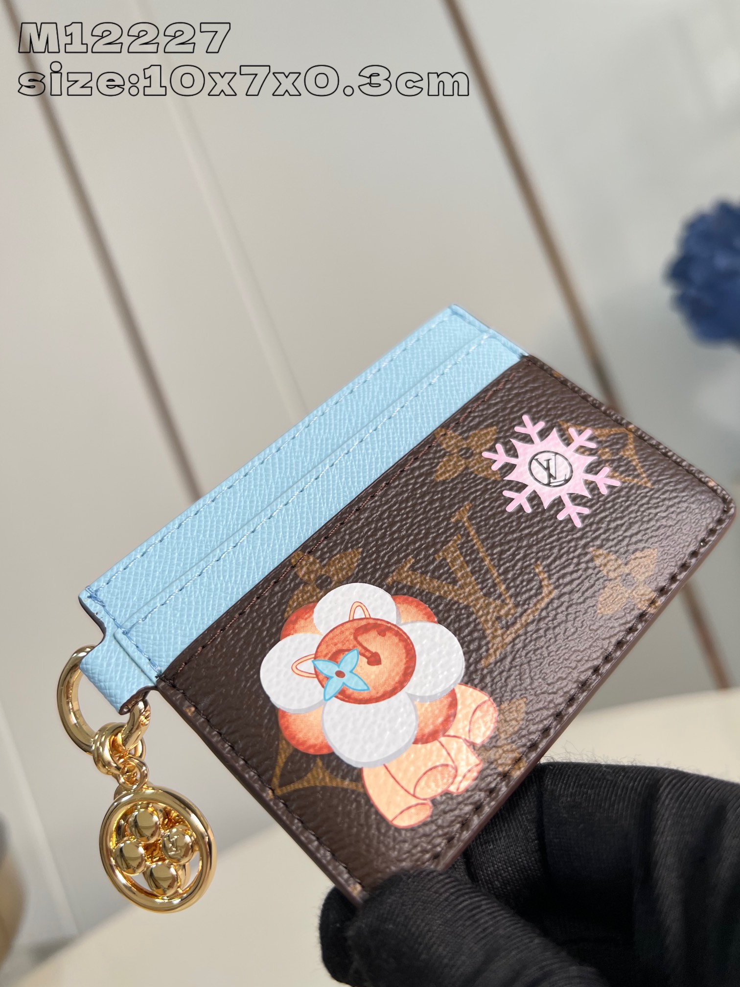 M12227 A festive reinterpretation of the Snow Show collection, this LV Charms business card holder is crafted in classic Monogram canvas with smooth leather trim and festive illustrations, including the brand's mascot, Vivienne's puppy Petula. The small size is perfect with the Vivienne-shaped charm and LV floral design. 10.2 x 7.3 x 0.3 cm (L x H x W)