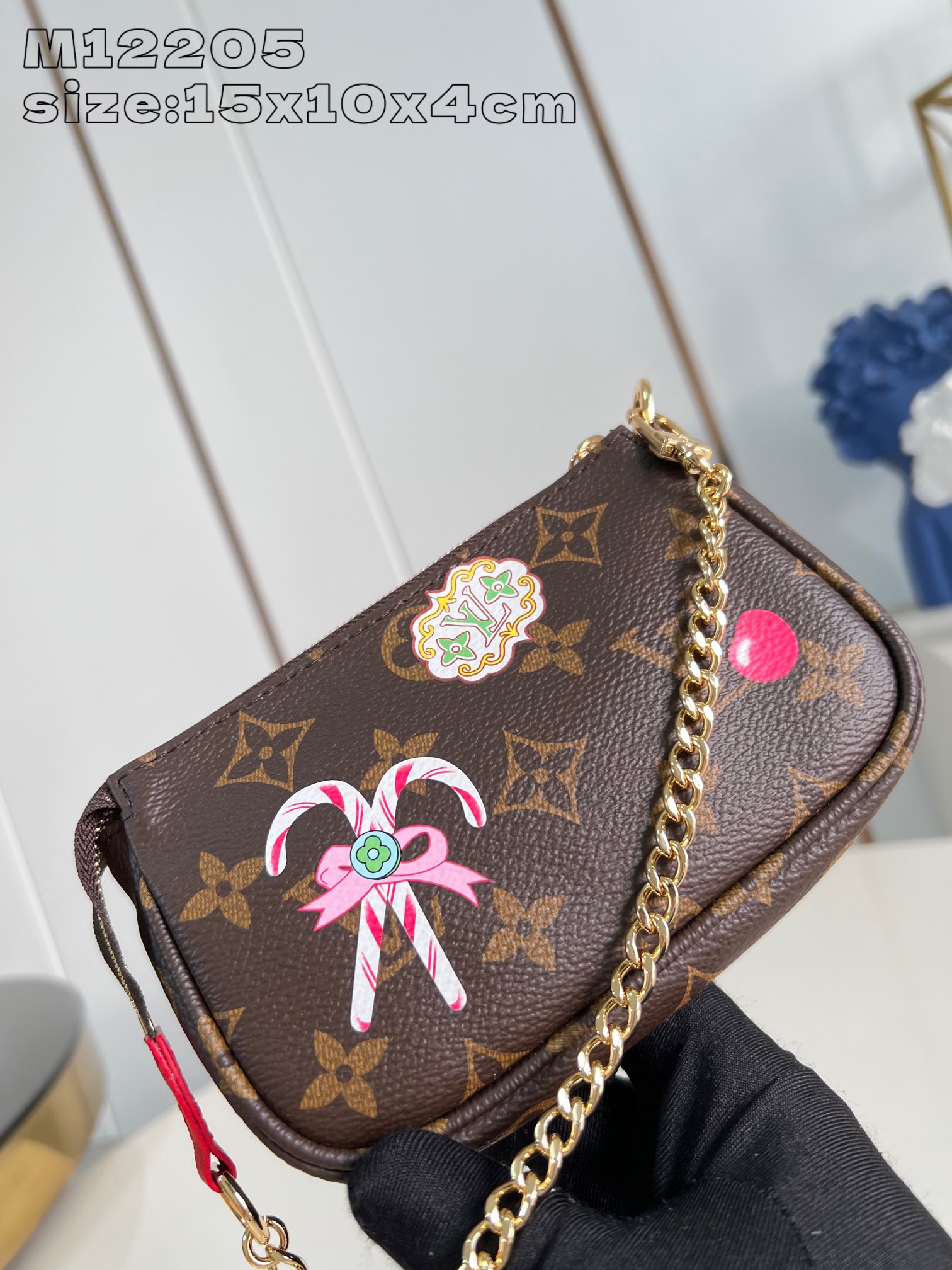 M12205 Esta festiva Mini Pochette Accessoires de la colección Candy Factory está adornada con simpáticos motivos como la icónica muñeca Vivienne dándose un baño en una jarra caliente, y está confeccionada en la emblemática lona Monogram de Louis Vuitton. Está decorada con un forro Candy rojo brillante y acabada con una cadena dorada de cierre autoadherente y una cremallera con forma de Vivienne. Diseño con cremallera en forma de Vivienne 15,5 x 10,5 x 4 cm (largo x alto x ancho)