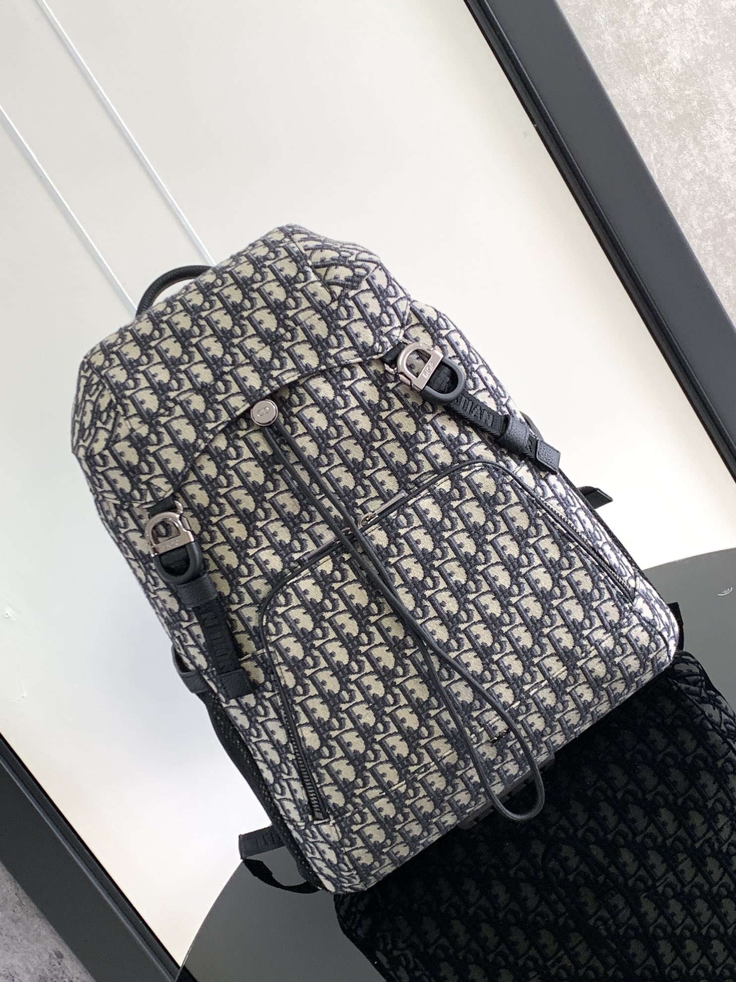 P 1220 Esta mochila Dior 8, novidade da coleção masculina verão 2014, homenageia o fabuloso ar livre e o estilo Dior com seu design de aba. Confeccionada em tecido estampado Oblique bege e preto, o compartimento principal tem uma aba com fecho Dior 8 para guardar os itens essenciais do dia a dia, um bolso frontal com zíper e bolsos laterais em tecido de malha para facilitar o acesso às suas chaves ou fones de ouvido, tornando-a prática para uma grande variedade de looks. Um complemento prático e versátil para qualquer lookEstampado oblíquo bege e pretoLogótipo Dior gravado em relevo no interiorAlça de ombro ajustável em tecido de malha acolchoadaPegas em peleMalha técnica acolchoada reforçada com o logótipo Dior no fundo da bolsaFecho de aba com 2 fivelas Dior 8Bolso frontal com fecho de correr2 bolsos laterais em tecido de rede na parte lateralBolso interior com fecho de correrSaco para o pó incluídoReference: 1EIBA187YKY_H27E1213Dimensões: 31 x 50 x 18 cm