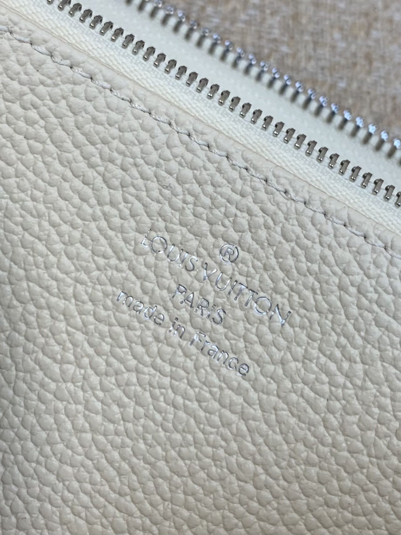 M12680 Le "Porte-monnaie Claire" de la collection "L*SKI" est de couleur beige et de finition brillante. La couleur Azur Frost, exclusive cette saison, crée une atmosphère raffinée. Monogramme/fleur sur la fermeture éclair Taille : 11x8.5x3.5cm-Fabrication haute couture