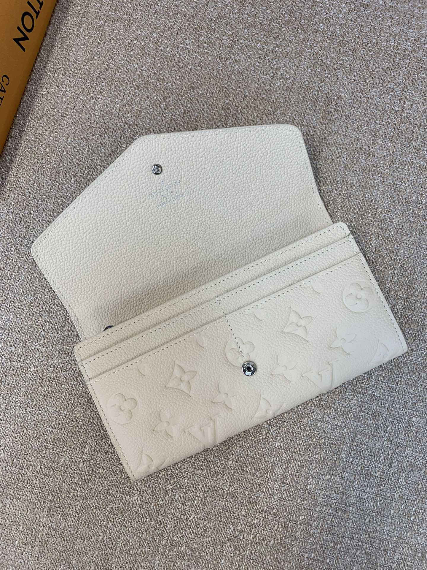 M12172 Beige As part of LV's ski collection, this "shiny" version of the Sarah Wallet is also ideal for alpine escapes and days on the town The envelope-inspired design showcases the house's signature Monogram Empreinte leather and is secured with a press-stud fastening decorated with a single Monogram flower. Secured with a press-stud closure decorated with a single Monogram flower Inside, there are multiple pockets and compartments for bills and coins, plus 16 card slots Size: 19x10.5x2cm-High Fake Factory