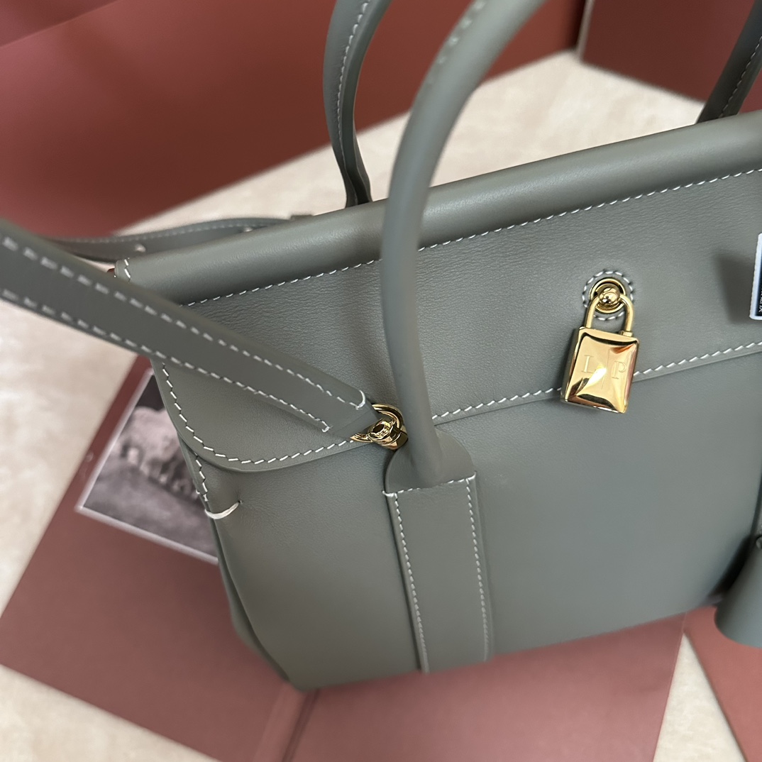 💰2240Loom L25 Small Tote Color: Verde BrilloEl bolso Loom rinde homenaje a la larga herencia textil de Loro piana, con una barra metálica bajo la solapa que recuerda el tejido cayendo suavemente del telar de un artesano, un elegante tributo a las célebres técnicas de tejido de la marca. Confeccionado en piel de vacuno ligera y de textura característica, el bolso lleva un delicado cierre de candado que puede abrirse para un look informal. Tamaño: 25✖️18✖️12.5CM-Altura de imitación de fábrica