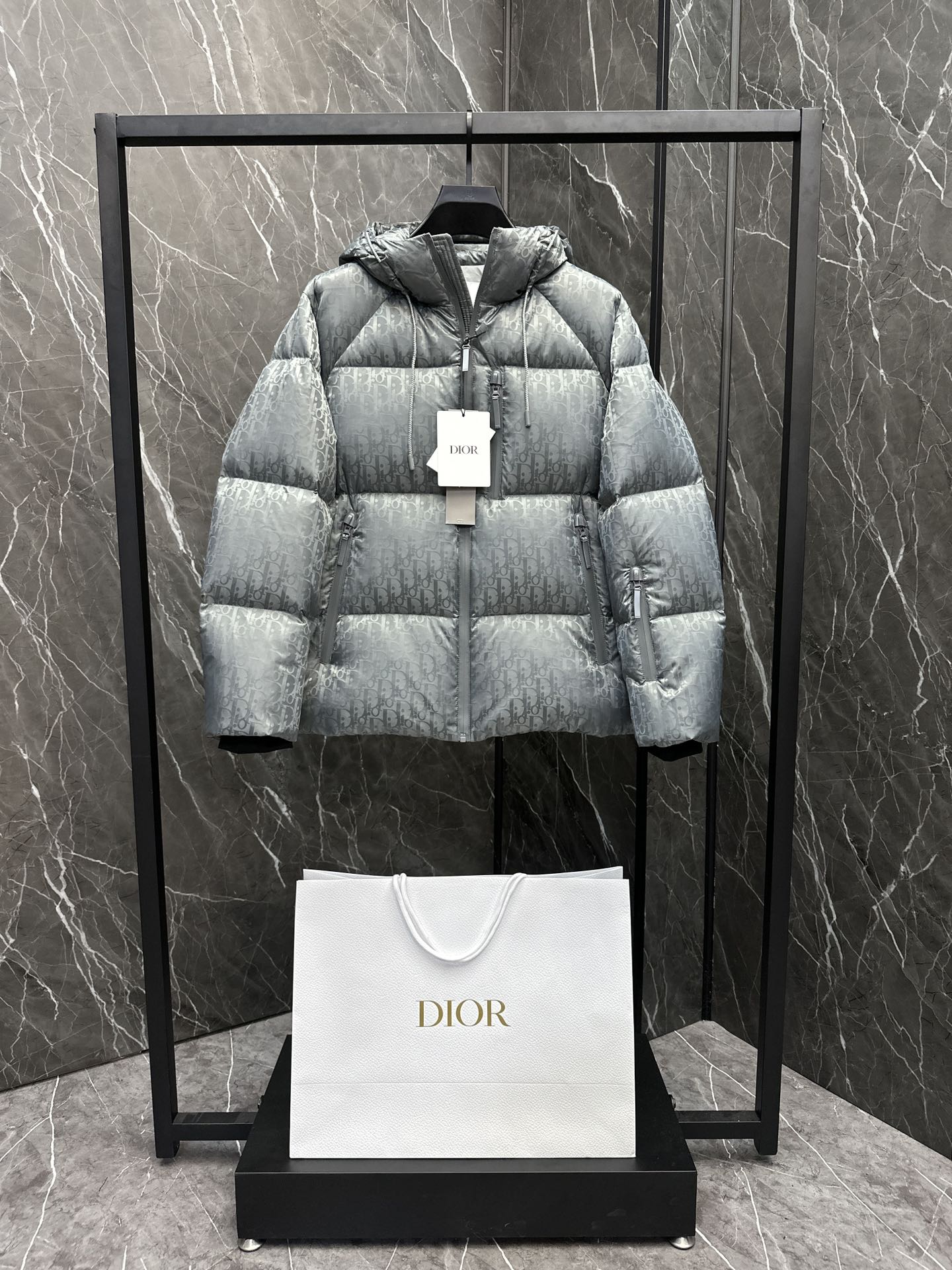 P1360 Dior CD Diorテックファブリック 斜めプリントフードダウンジャケット。中わたはグースダウン。スーパーフル。冬のための一着。ディオールの伝統に敬意を表し、同系色のObliqueプリントを施したテクノジャカード製のダウンジャケット。 カジュアルでありながらスタイリッシュなこのアイテムは、防風コンプレッションジッパーで開閉し、中わたには暖かいグースダウンを使用。-防風コンプレッションファスナーDiorロゴ刻印入りジップファスナー ・サイドにパッチポケットと内ポケット ・中綿：90%ホワイトグースダウン 10%ホワイトグースフェザー ・素材：100%ナイロン（トリムを除く） ・素材2 100%ナイロン、刺繍 ・素材3 100%ナイロン、刺繍 ・素材4 100%ナイロン、刺繍 ・素材50%ナイロン。50% PVC素材3 100%ポリエステル-イタリア製サイズ : 48-56ブラック/グレー-ハイファッションバッグ