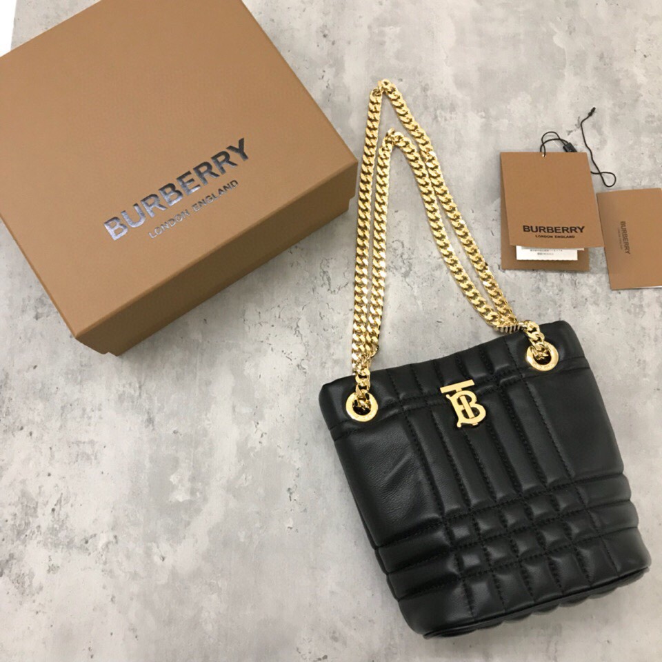 El bolso acolchado "Lola - Lorna Bag" de Burberry, sumamente suave y chic, está confeccionado en Italia con piel de cordero curtida y decorado con el logotipo exclusivo de Thomas Burberry y una brillante correa de cadena que puede llevarse colgado del hombro o como una pieza holgada Modelo: Mini bolso de cubo Dimensiones: 20 x 9 x 16 cm p900