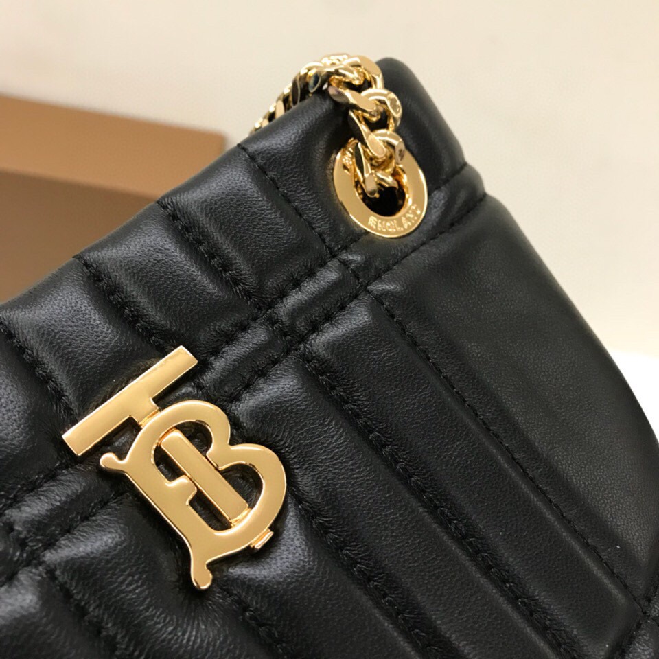 Le sac Lola - Lorna de Burberry est un sac matelassé chic et extrêmement doux, fabriqué en Italie à partir de peau d'agneau tannée et décoré du logo exclusif de Thomas Burberry et d'une bandoulière en chaîne brillante qui peut être portée à l'épaule ou en bandoulière. Modèle : Mini sac Bucket Dimensions : 20 x 9 x 16 cm p900