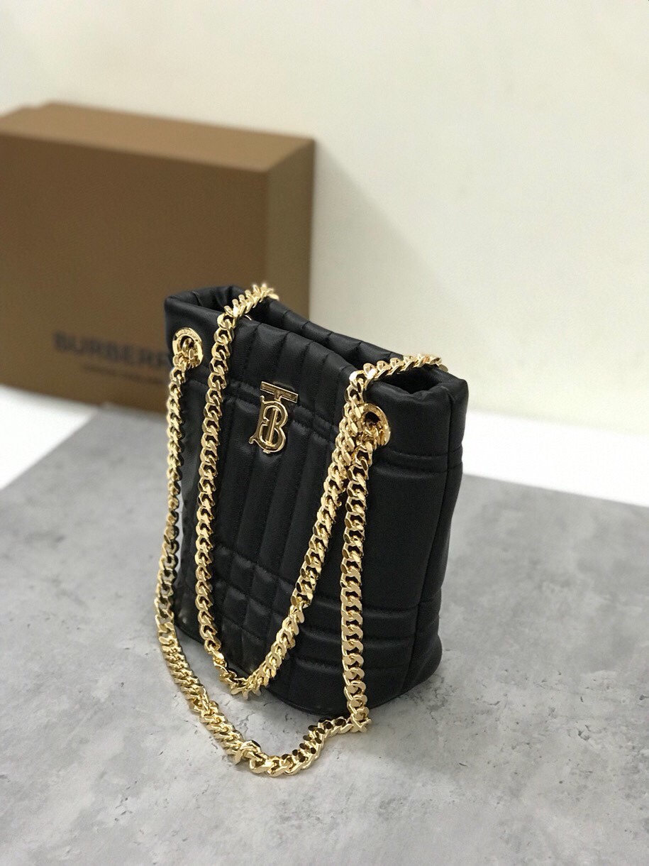 El bolso acolchado "Lola - Lorna Bag" de Burberry, sumamente suave y chic, está confeccionado en Italia con piel de cordero curtida y decorado con el logotipo exclusivo de Thomas Burberry y una brillante correa de cadena que puede llevarse colgado del hombro o como una pieza holgada Modelo: Mini bolso de cubo Dimensiones: 20 x 9 x 16 cm p900