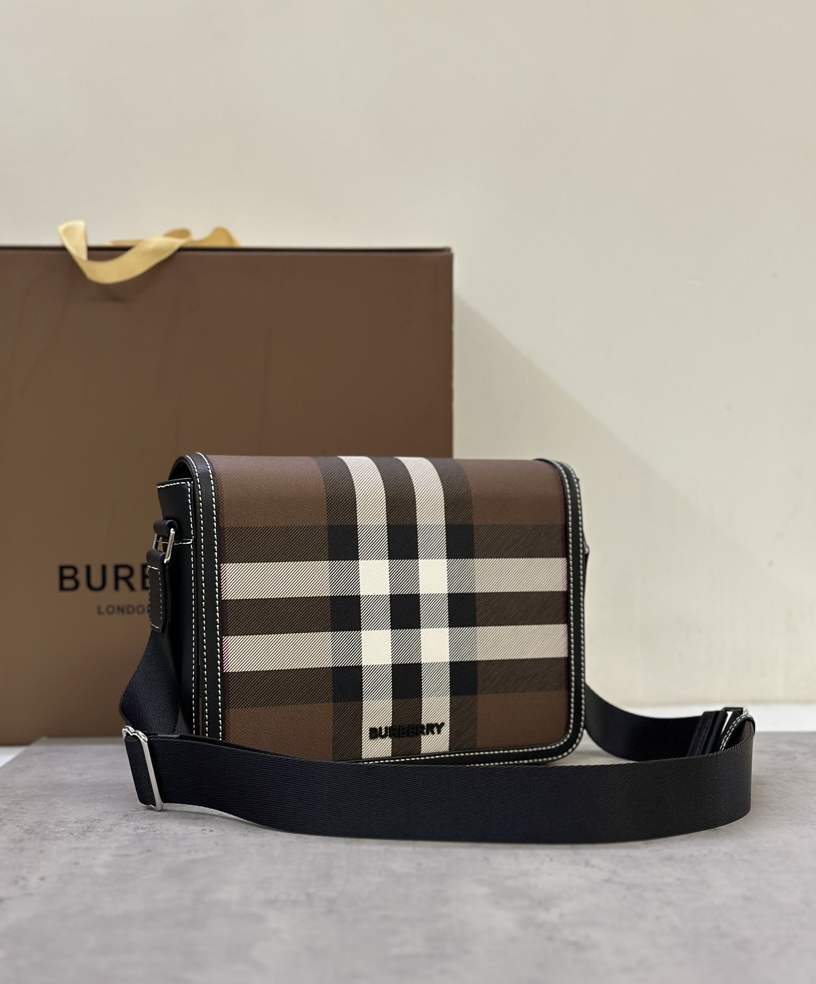 Burberry messenger bagSophisticated stand-up designDecorated with Burberry check pattern with leather trim and brand logo25.5 x 6.5 x 21.5cm.Adjustable shoulder strap.1 external slip pocket; 1 internal slip pocket. Top flap with magnetic closure. Hand-painted edges. Burberry logo p1000 on front.