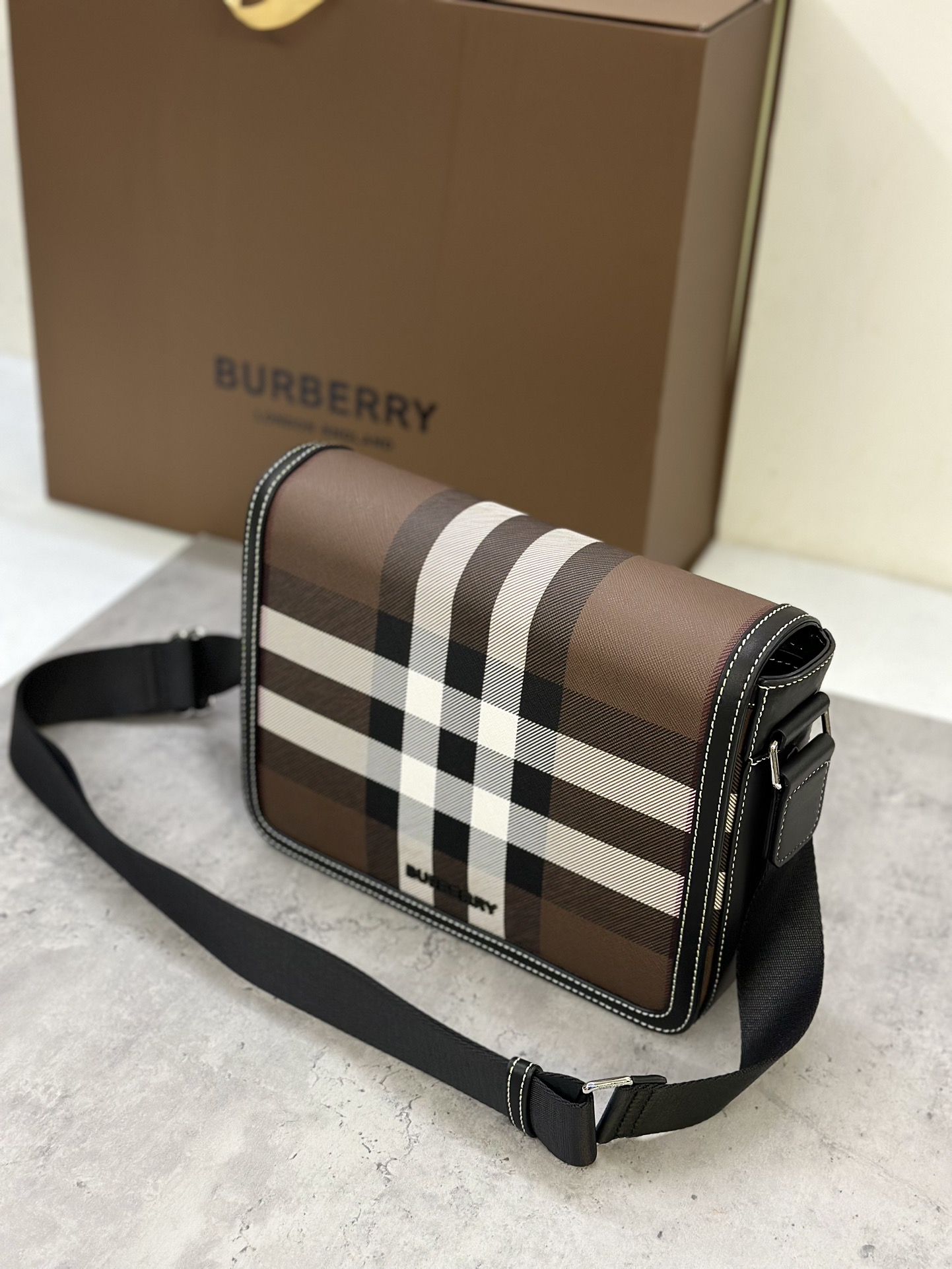 Burberry messenger bagSophisticated stand-up designDecorated with Burberry check pattern with leather trim and brand logo25.5 x 6.5 x 21.5cm.Adjustable shoulder strap.1 external slip pocket; 1 internal slip pocket. Top flap with magnetic closure. Hand-painted edges. Burberry logo p1000 on front.