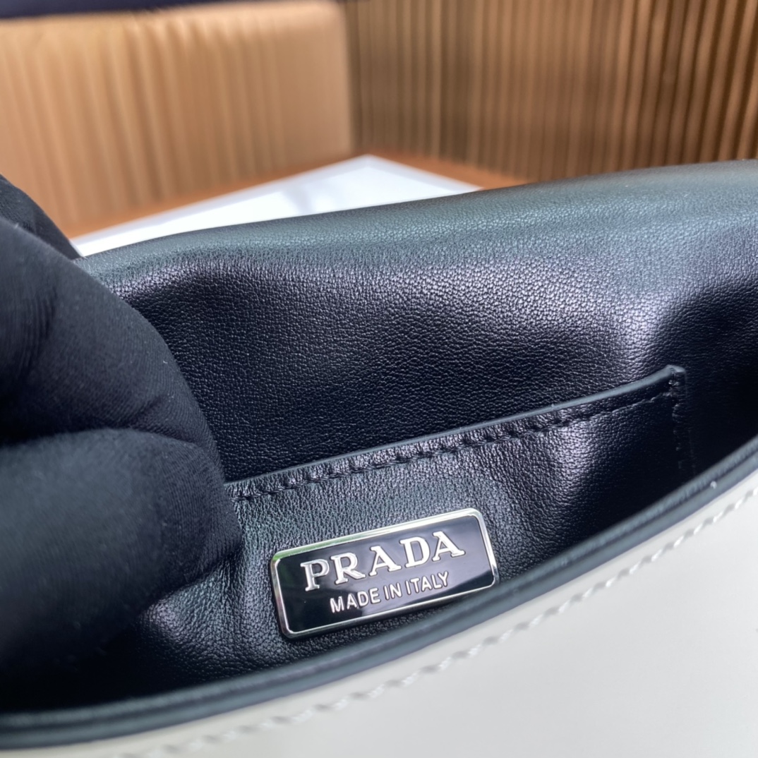 P1100 Prada Bolsa para telemóvel em pele branca brilhante 2VD061 Super versátil e com bom aspeto, o hipster chique tem de a comprar! Inspirada na coleção CleA estrutura lateral angular única cria uma silhueta minimalistaA aba é adornada com um logótipo prensado a quenteA bolsa geral é minimalista mas eleganteO interior tem um pequeno bolso de remendoTamanho:18*12,5*2,5 cm