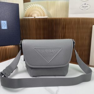 P1420 Prada 灰色邮差包2VD056
这款粒面牛皮邮差包演绎精美的结构式廓形
正面3D立体效果全新三角形徽标
侧面经典三角搪瓷徽标
顶部翻盖开合两侧贴心口袋
可调式全皮肩带
更是凸显独特气质百搭休闲
时尚潮男必备
size：22*22*12cm

​-高仿包包