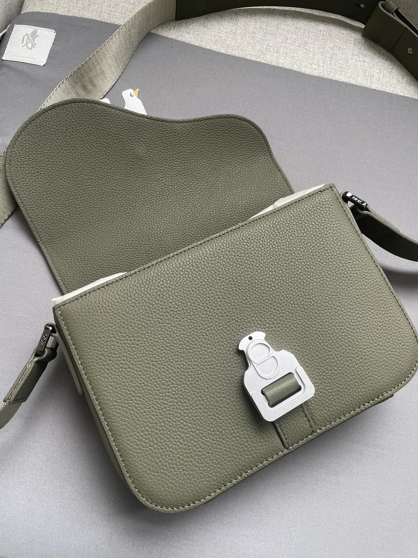 Esta elegante e moderna bolsa mensageiro com sela é confeccionada em couro de vaca cáqui granulado com uma aba de sela e fecho de fivela de alumínioCompartimentos interiores espaçosos e um bolso com fenda na parte de trás para guardar seus itens essenciais diáriosEstilo menor com alça de ombro ajustável em couro e jacquard com o logotipo Christian DiorPara ombro ou corpo cruzadoModelo nº 8018Medidas23-18-6Compartimento principal com aba e logotipo CDFivela de alumínioInterior Bolso com ranhuraBolsa com ranhura atrásAlça de ombro ajustável em couro e com logótipo Christian Dior em jacquard de nylonLogotipo Dior em relevo no interiorSaco para o pó incluídoFabricado em Itália191701100-Bolsas de alta qualidade