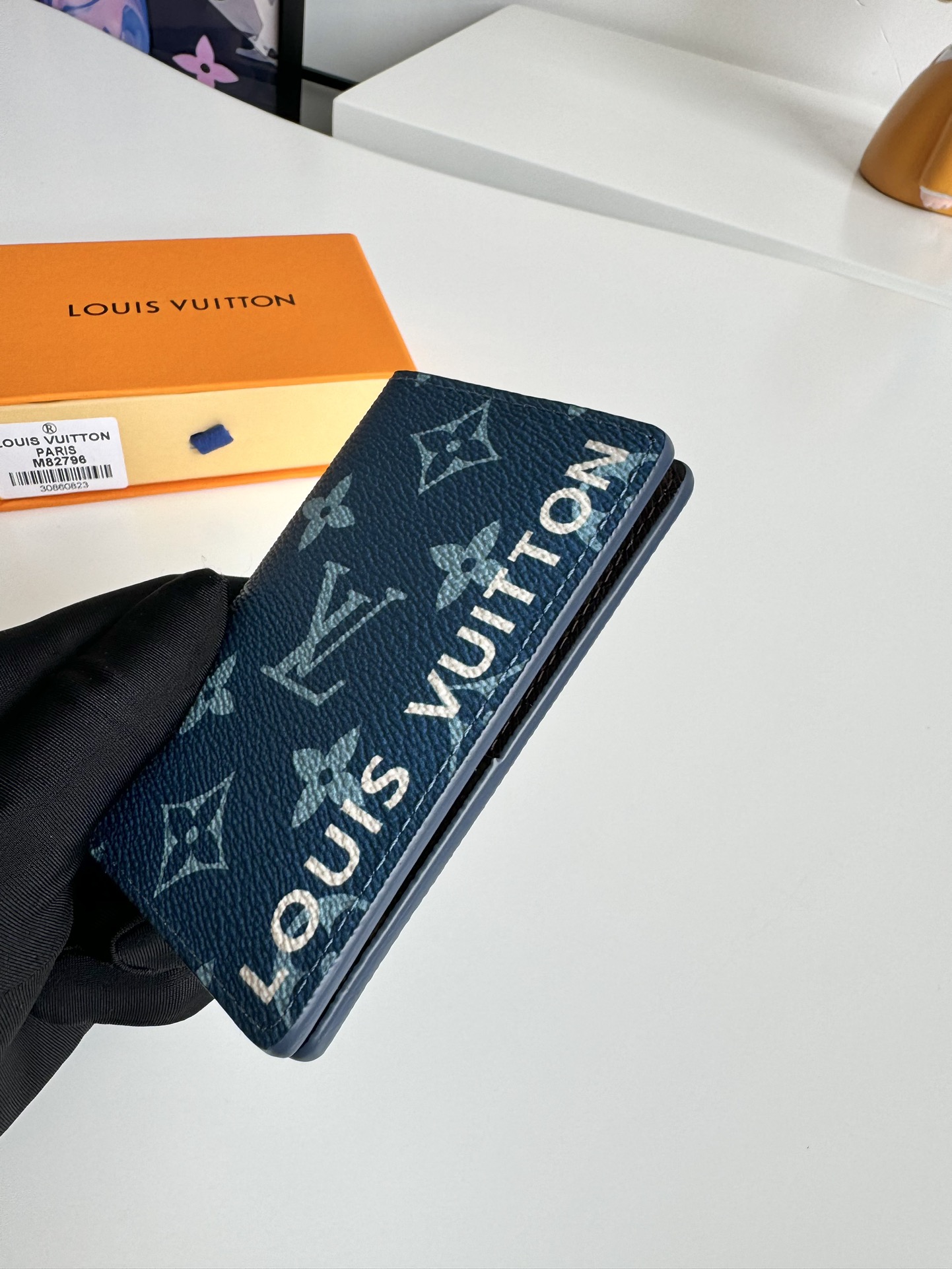 P360 M82796 This pocket wallet is made of smooth Monclerogram-coated canvas with a contrasting color lining and Louis Vuitton lettering on the side in portrait orientation. Its compact shape conceals a wealth of functions.