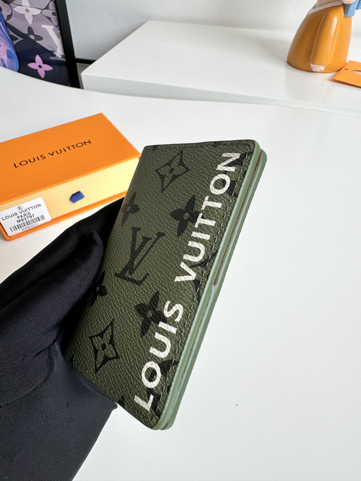 P360 M82797 This pocket wallet is made of smooth Monclerogram-coated canvas with a contrasting color lining and Louis Vuitton lettering on the side in portrait orientation. Its compact shape conceals a wealth of functions.