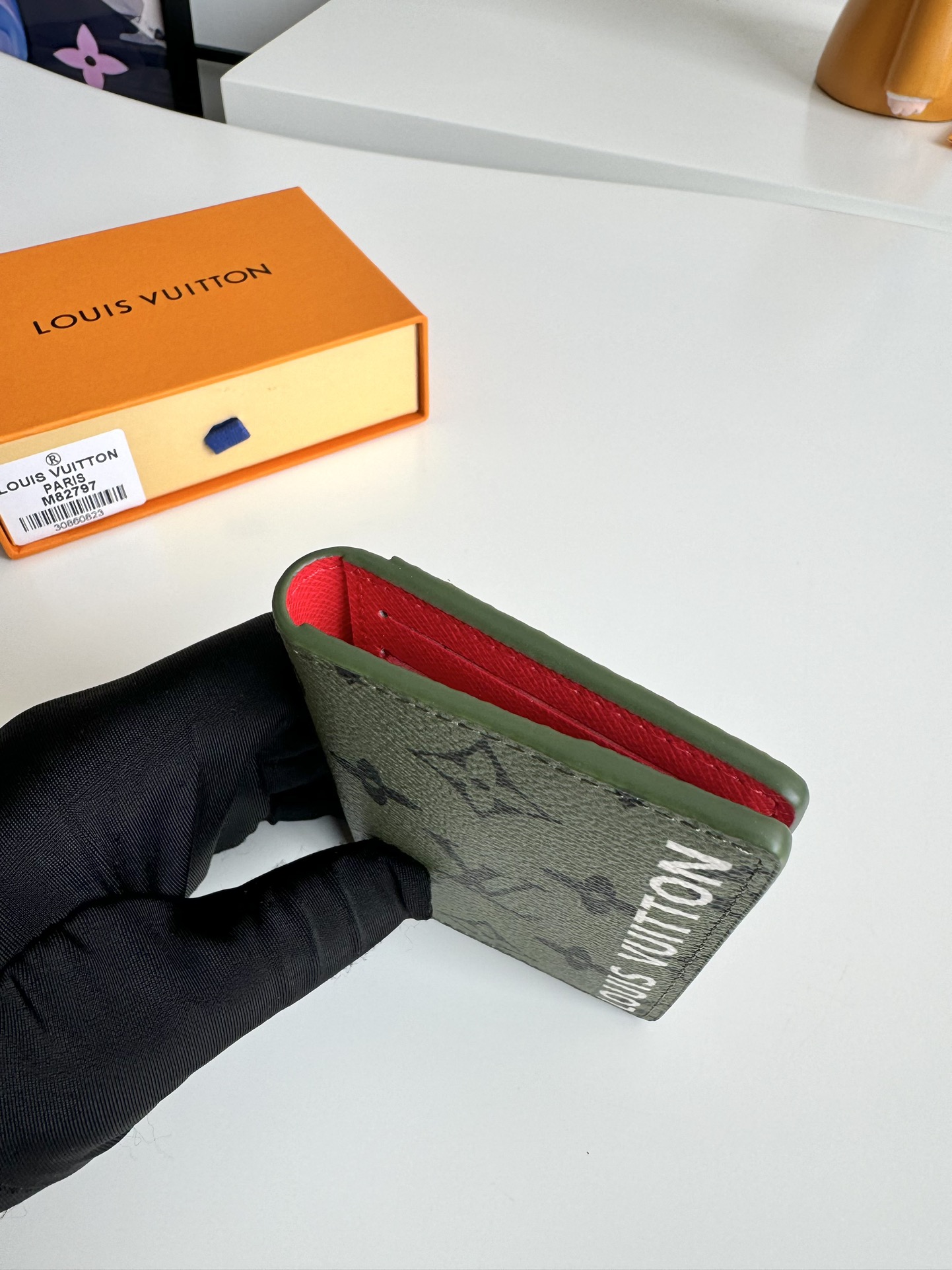 P360 M82797 This pocket wallet is made of smooth Monclerogram-coated canvas with a contrasting color lining and Louis Vuitton lettering on the side in portrait orientation. Its compact shape conceals a wealth of functions.