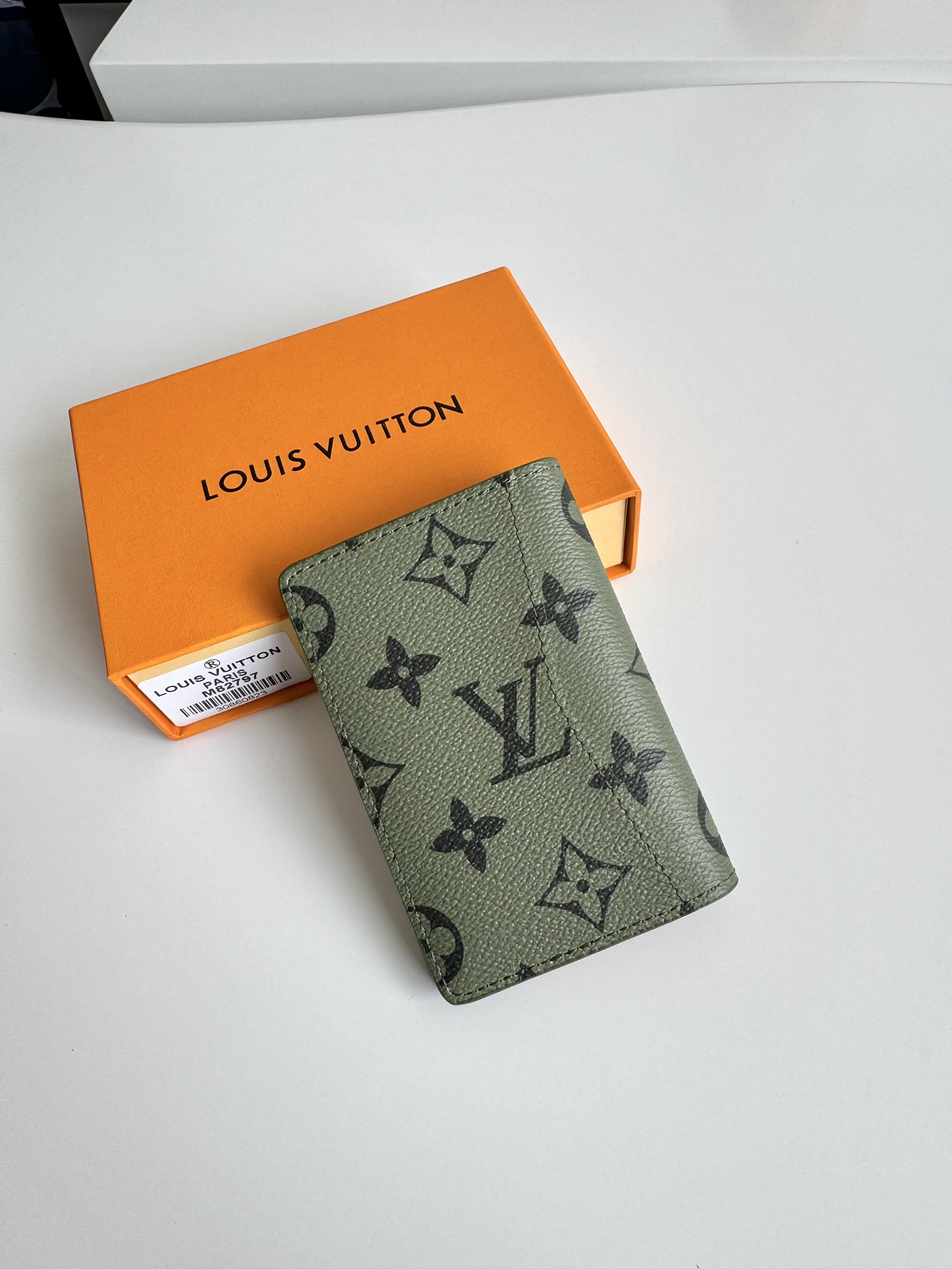 P360 M82797 This pocket wallet is made of smooth Monclerogram-coated canvas with a contrasting color lining and Louis Vuitton lettering on the side in portrait orientation. Its compact shape conceals a wealth of functions.