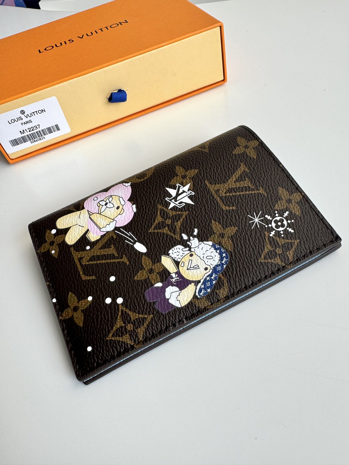 P320 M12219 Este porta-passaportes apresenta a mascote da marca, Vivienne, revelando o sabor funky da coleção Snow Show numa tela Monclerogram representando flocos de neve LV e um bonito urso polar forrado a pele com detalhes apelativos Bolsos com pala e um compartimento para cartões para uma organização organizada Dimensões: 14 x 10 x 2,5 cm