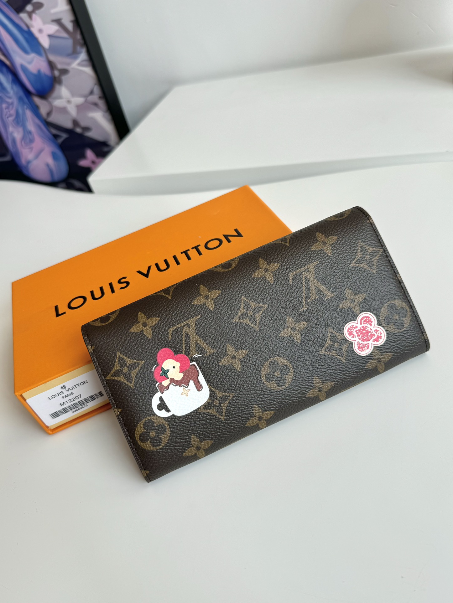 P460 M12207 This envelope wallet is made of elegant Monclerogram canvas and features the brand's mascot, Vivienne, to showcase the Snow Show collection's playfulness. The interior is smart and unique, with a variety of pockets and credit card slots. 19 x 9.5cm.