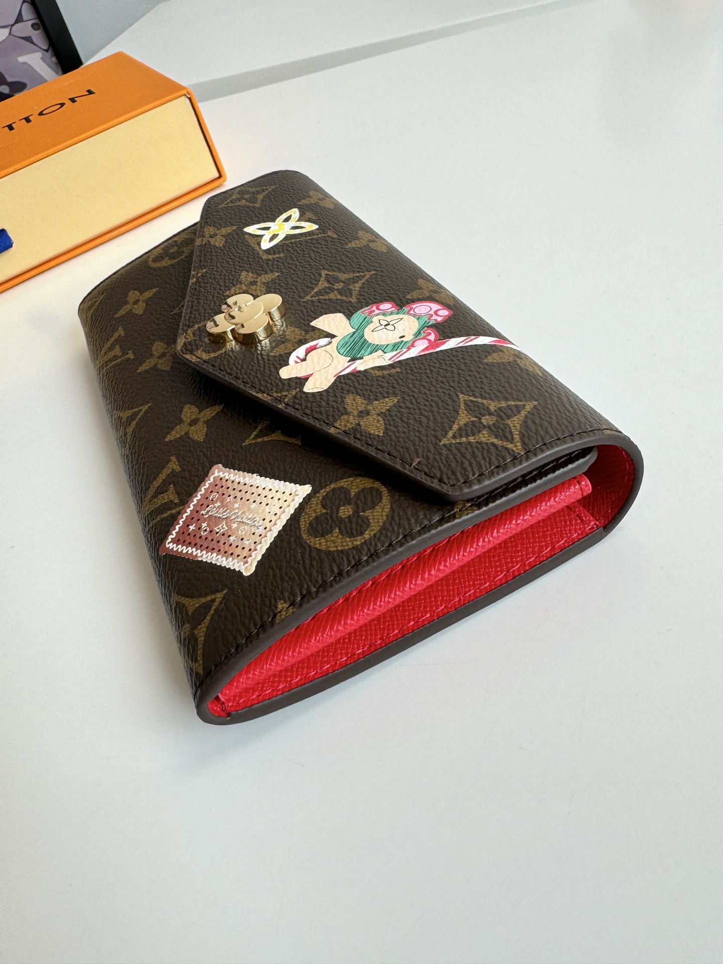 P460 M12207 This envelope wallet is made of elegant Monclerogram canvas and features the brand's mascot, Vivienne, to showcase the Snow Show collection's playfulness. The interior is smart and unique, with a variety of pockets and credit card slots. 19 x 9.5cm.