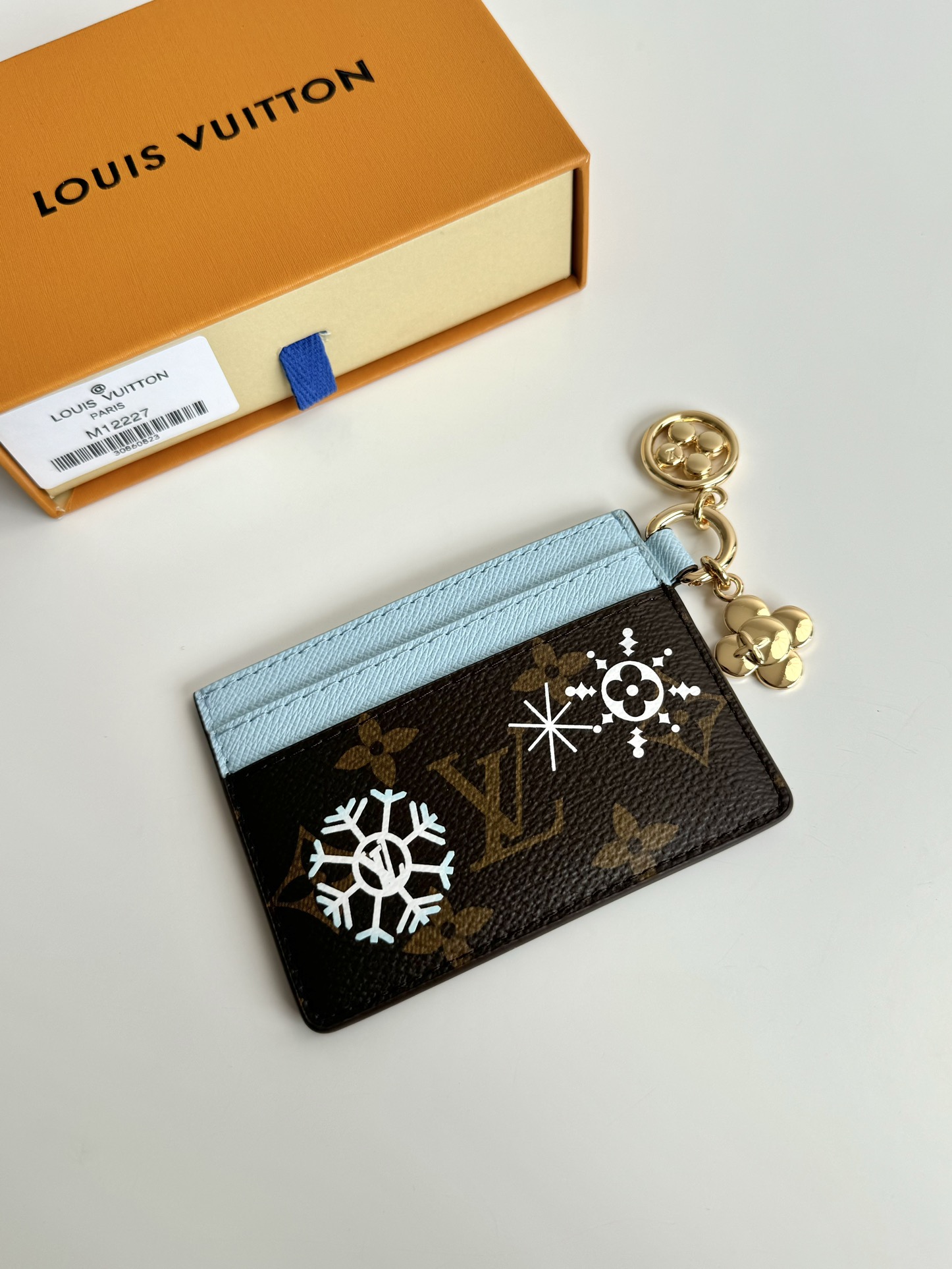 P320 M12215 This LV Charms card holder from the Candy Factory collection invites the brand's mascot to celebrate the holiday season Monclerogram canvas depicts Vivienne wandering through a joyful landscape of colorful candies Vivienne styling embellishments and LV floral detailing Dimensions: 10 x 7.3cm.