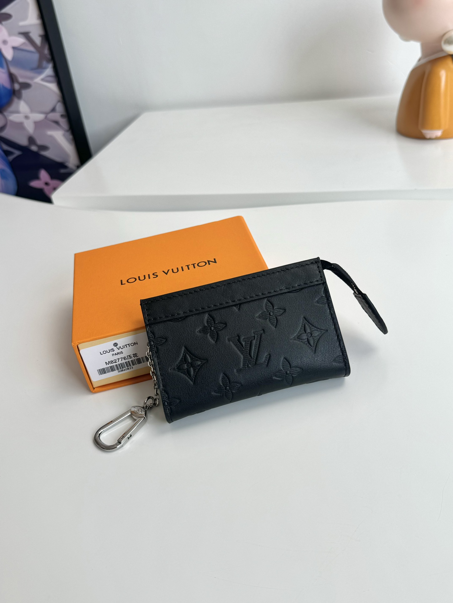 P440 M82776 Embossed Este porta-chaves Voyage é fabricado em pele macia de Taurillon com acabamentos em pele de vaca e um fecho de correr para guardar em segurança moedas, notas dobradas, cartões e chaves. O gancho e a argola para chaves são convenientemente fixados no interior da mala Louis Vuitton com uma argola em D. Dimensões: 12 x 7,5 x 3 cm