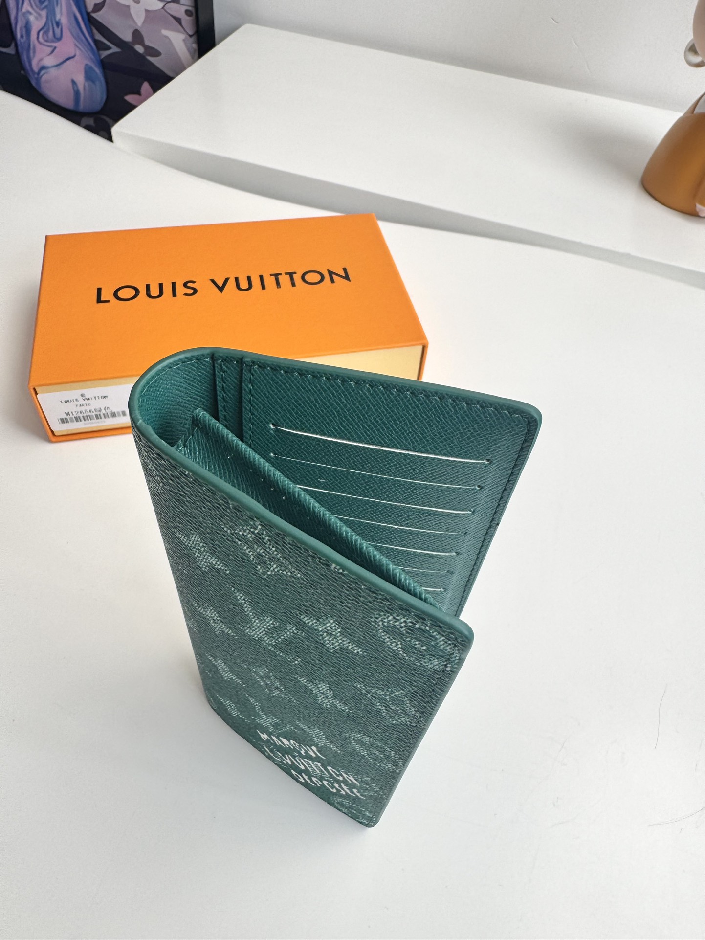 P400 M12656 Verde En esta cartera Brazza de lona Monclerogram Heritage, Pharrell Williams reinterpreta el icónico estampado Monclerogram con texturas entrecruzadas y el logotipo de la Marque L. Vuitton Déposée luciendo el estampado Damier original. Los elementos clásicos del estampado Damier original se combinan con múltiples ranuras para tarjetas y compartimentos para un diseño largo y funcional Tamaño: 19 x 10 x 2 cm