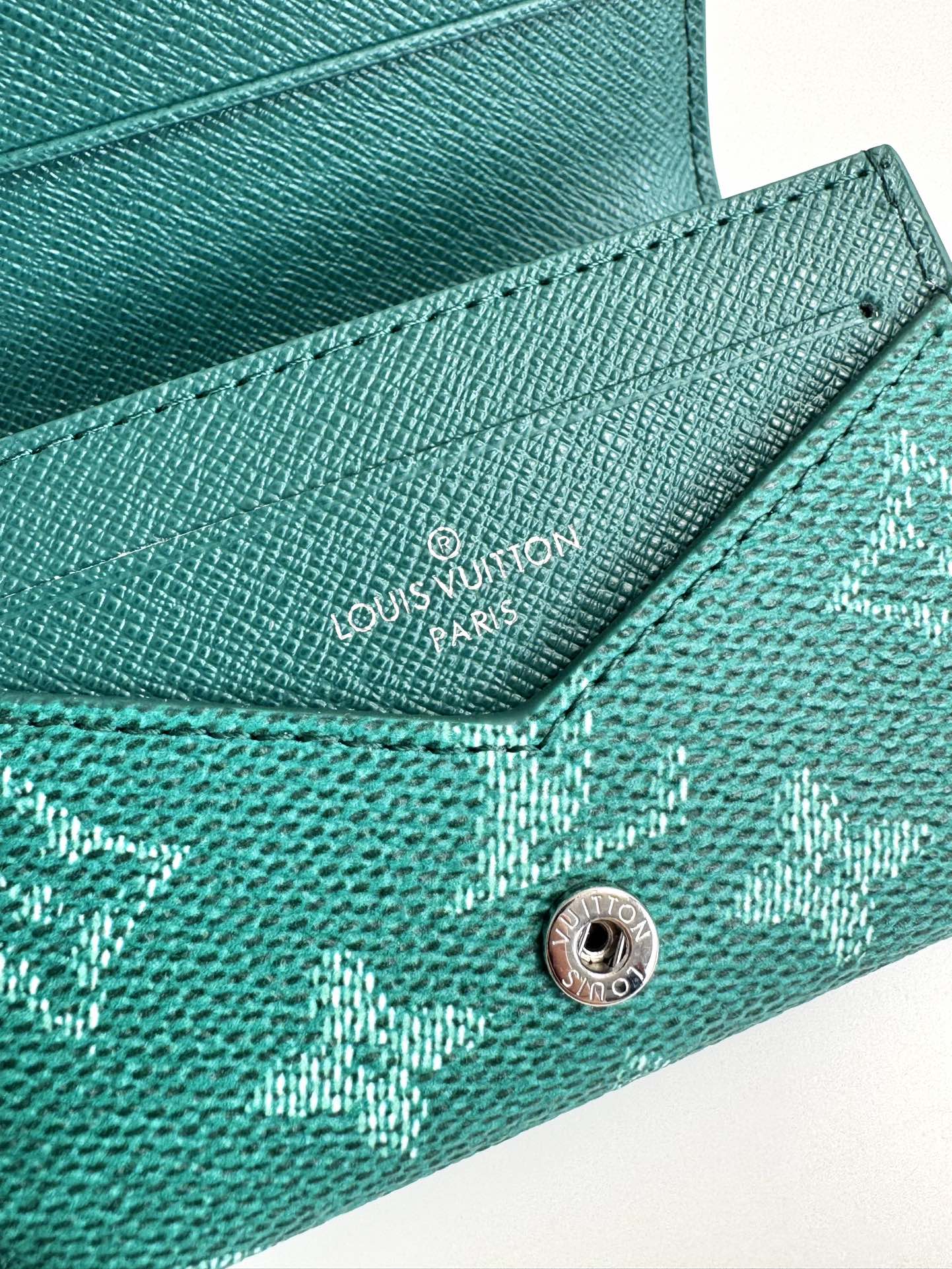 P320 M12664 Green This business card holder in Monclerogram Heritage canvas has a slim silhouette and can be easily slipped into a pocket or handbag flap. It opens with a hidden snap closure that reveals an organza compartment and card slots. Cowhide leather lining and the Marque L.Vuitton Déposée logo in Damier canvas add sophisticated detailing to the size: 10.5 x 8 x 1cm