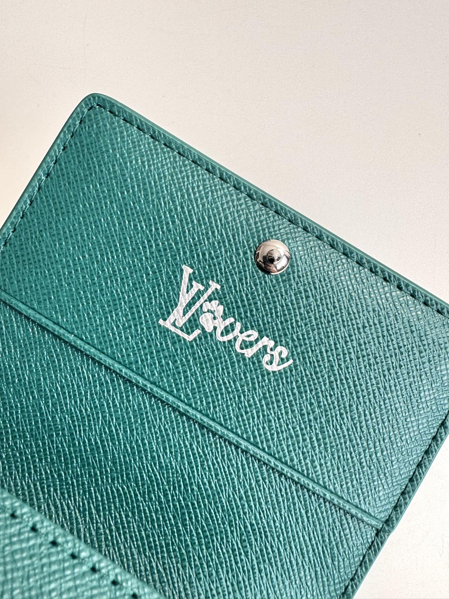 P320 M12664 Green This business card holder in Monclerogram Heritage canvas has a slim silhouette and can be easily slipped into a pocket or handbag flap. It opens with a hidden snap closure that reveals an organza compartment and card slots. Cowhide leather lining and the Marque L.Vuitton Déposée logo in Damier canvas add sophisticated detailing to the size: 10.5 x 8 x 1cm