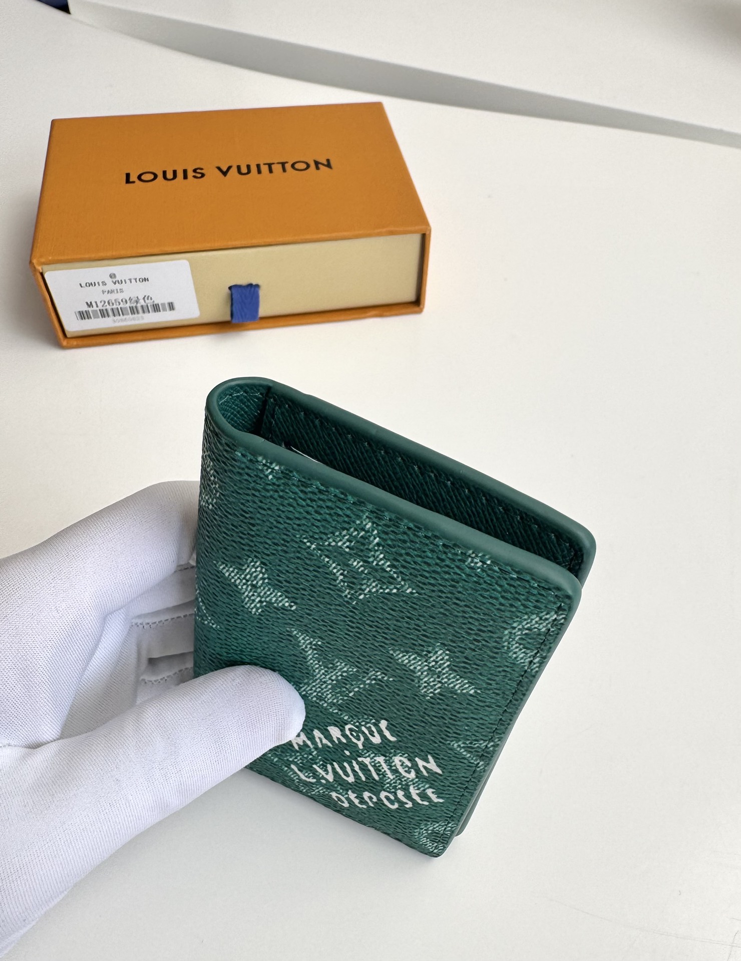 P280 M12659 Verde Esta cartera de bolsillo está confeccionada en lona revestida Monclerogram Heritage y presenta elementos clásicos como los cuadros Damier y el logotipo Marque L. Vuitton Déposée, mostrando la moderna interpretación de Pharrell Williams del estampado Monclerogram. 11 x 7,5 x 1 cm