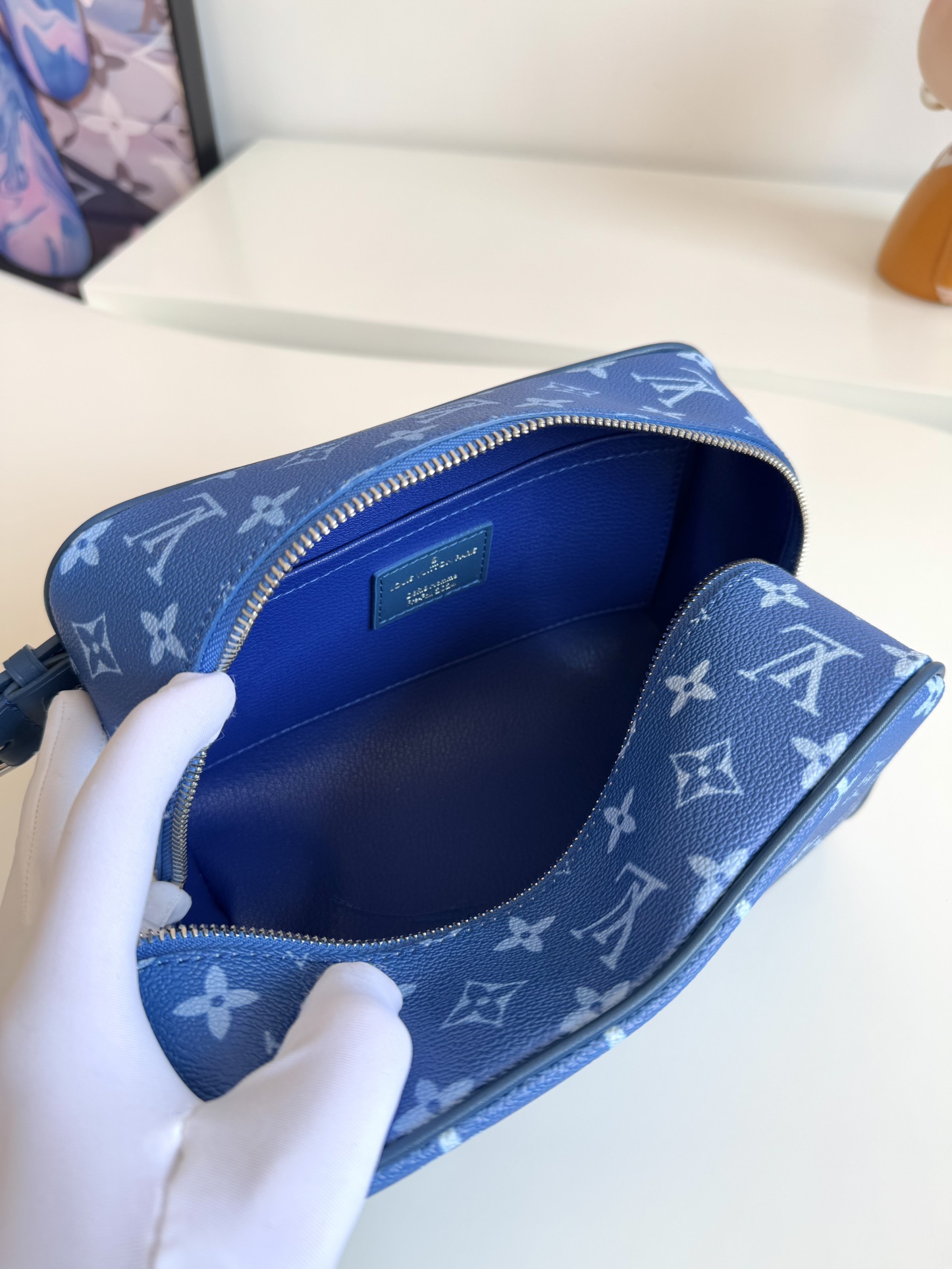 P720 M83112 NUEVO AZUL SEDA IMPRESO Este neceser Locker Dopp Kit está confeccionado en lona Monclerogram y es una mezcla de tendencias contemporáneas y elegancia. De forma compacta y con mucho espacio para guardar sus objetos de uso diario. El forro lavable combinado con las asas laterales ajustables facilitan su transporte.