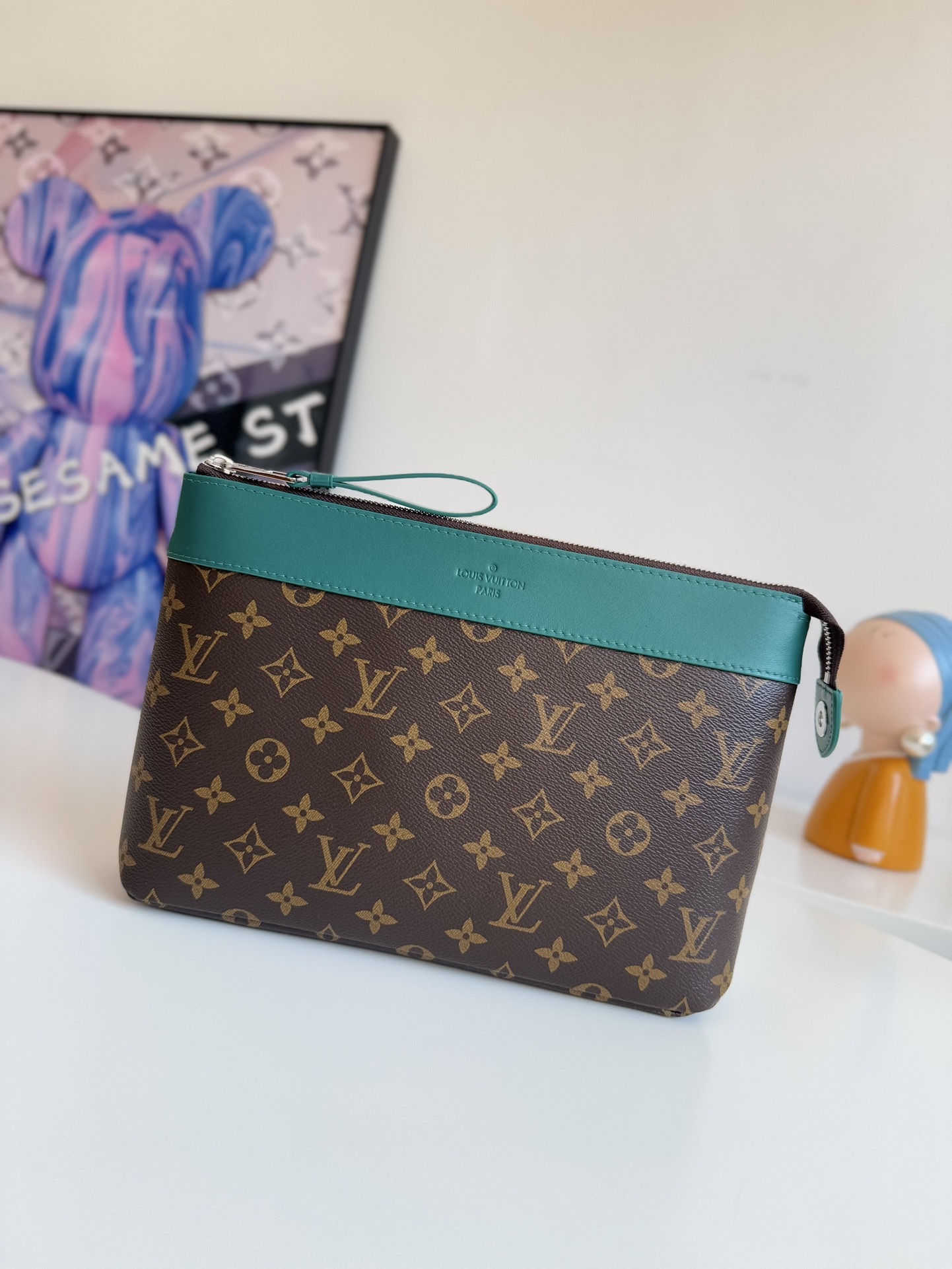 P720 M13356 Verde Este clutch Pochette Voyage Souple está confeccionado en la clásica lona revestida Monclerogram Macassar con adornos de piel de vacuno brillante y forrado en el mismo color para invocar el motivo del forro del estuche rígido tradicional de la marca. De construcción suave para lograr una organización ordenada que también puede incorporarse a un bolso grande.