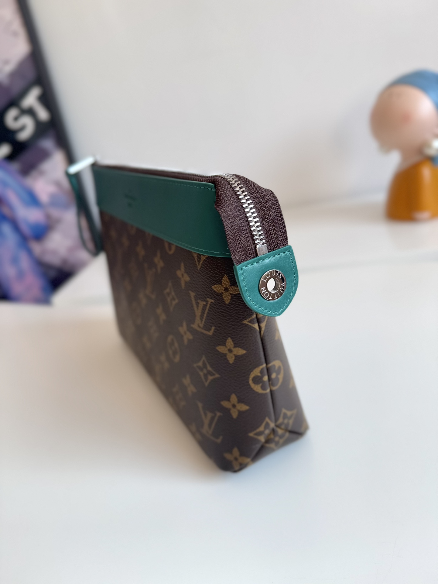 P720 M13356 Verde Este clutch Pochette Voyage Souple está confeccionado en la clásica lona revestida Monclerogram Macassar con adornos de piel de vacuno brillante y forrado en el mismo color para invocar el motivo del forro del estuche rígido tradicional de la marca. De construcción suave para lograr una organización ordenada que también puede incorporarse a un bolso grande.