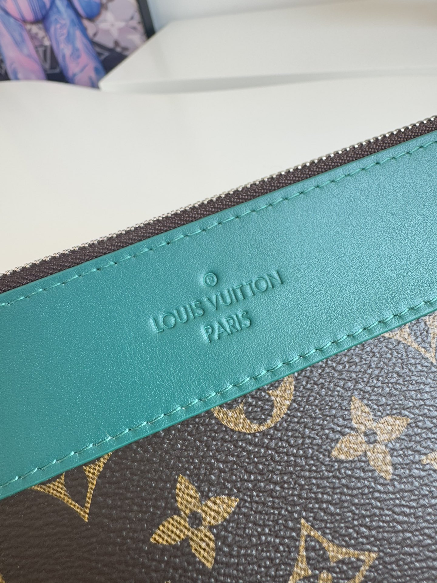 P720 M13356 Verde Este clutch Pochette Voyage Souple está confeccionado en la clásica lona revestida Monclerogram Macassar con adornos de piel de vacuno brillante y forrado en el mismo color para invocar el motivo del forro del estuche rígido tradicional de la marca. De construcción suave para lograr una organización ordenada que también puede incorporarse a un bolso grande.