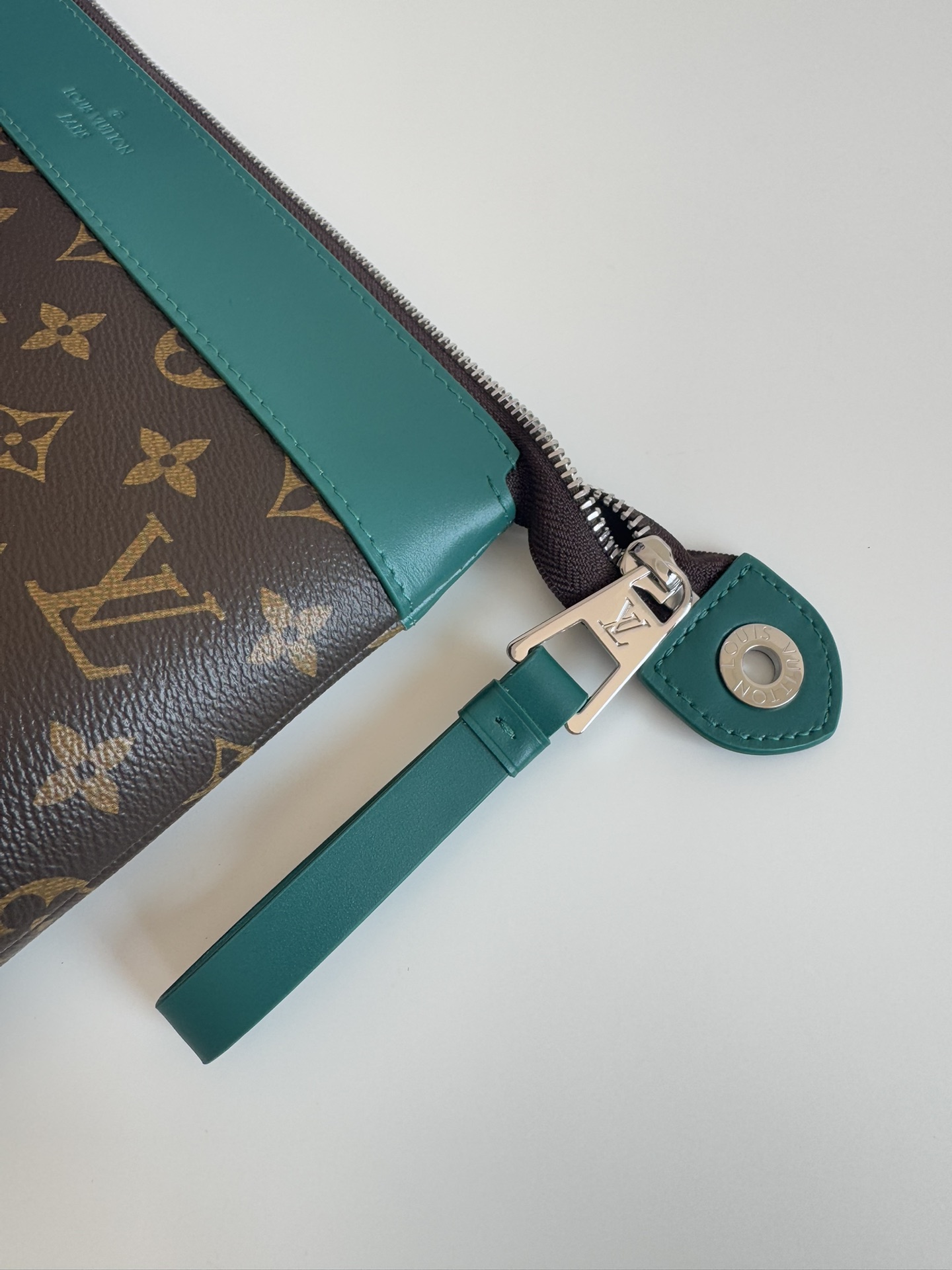 P720 M13356 Verde Este clutch Pochette Voyage Souple está confeccionado en la clásica lona revestida Monclerogram Macassar con adornos de piel de vacuno brillante y forrado en el mismo color para invocar el motivo del forro del estuche rígido tradicional de la marca. De construcción suave para lograr una organización ordenada que también puede incorporarse a un bolso grande.