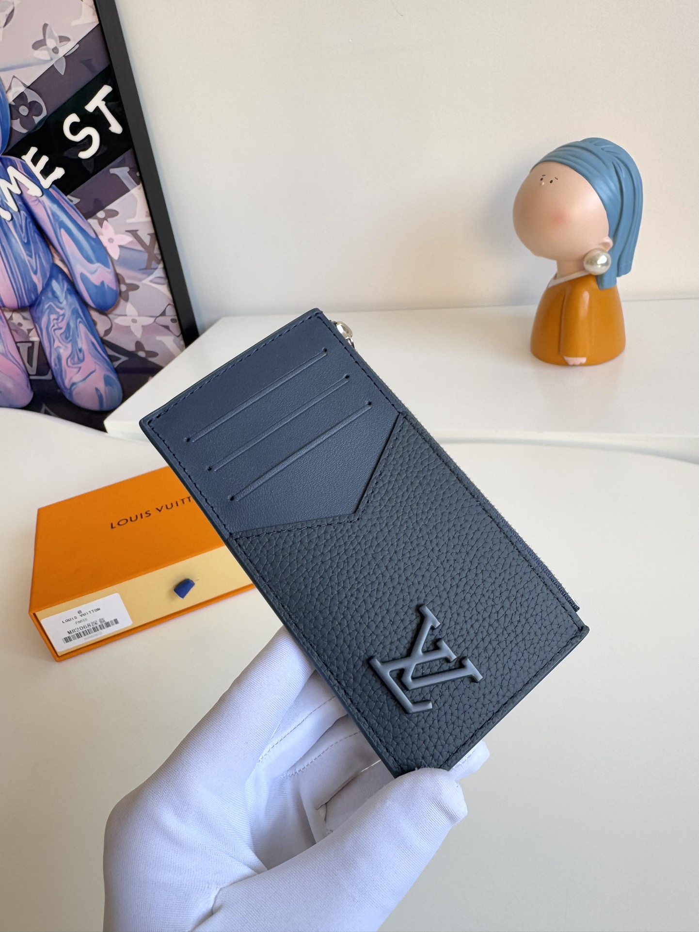 P360 M82068 Lake Blue Tailored from Louis Vuitton's iconic Taiga leather, the Coin card holder has a slim, clean look and is ideal for securely storing loose change and banknotes. Inside, there are multiple credit card slots and bill compartments, plus an additional zippered coin pocket.