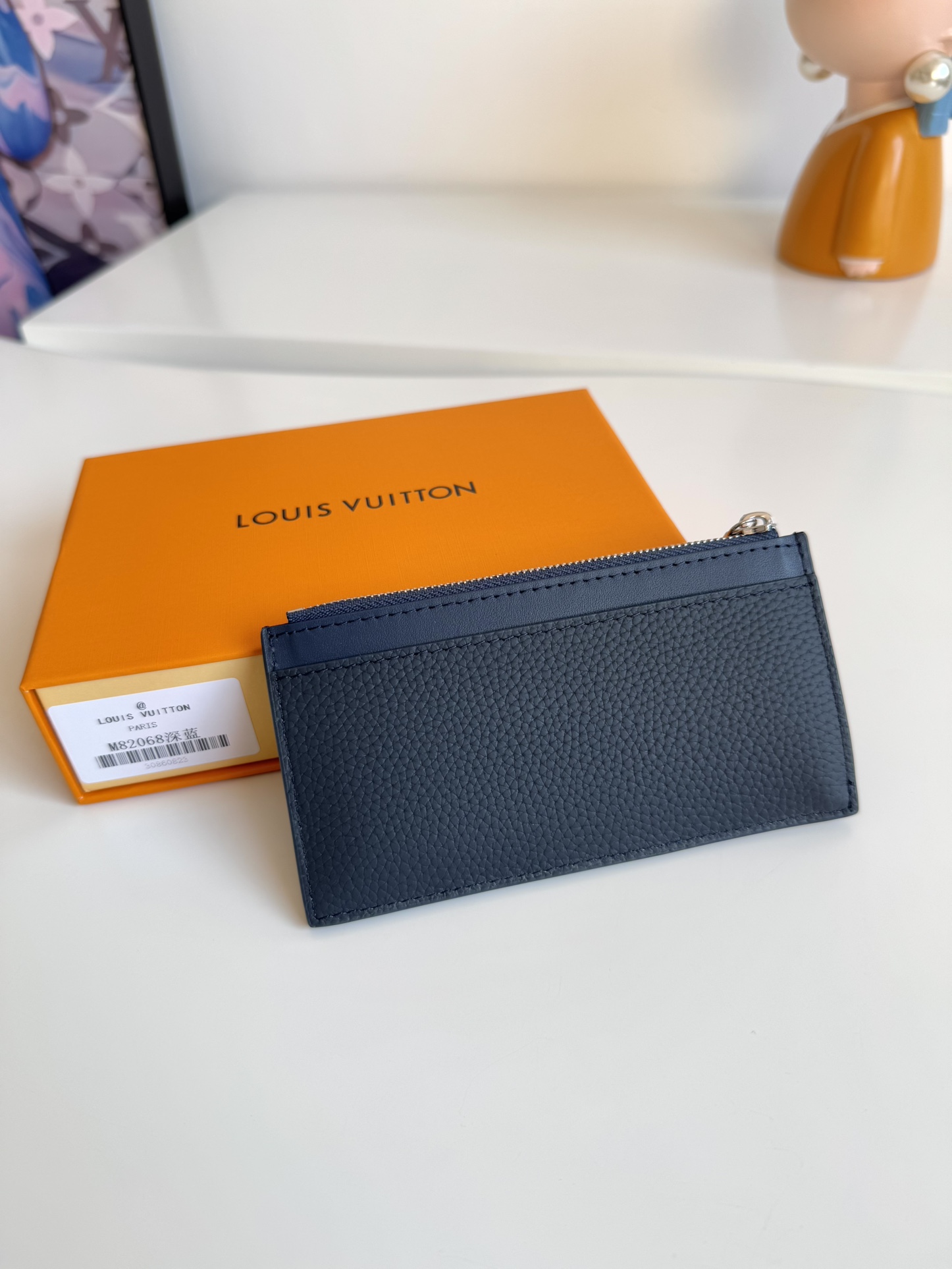 P360 M82068 Azul oscuro Confeccionado en la emblemática piel Taiga de Louis Vuitton, el tarjetero Coin tiene un aspecto elegante y limpio y es ideal para guardar de forma segura el cambio suelto y los billetes. En su interior hay múltiples ranuras para tarjetas de crédito y compartimentos para billetes, así como un bolsillo adicional con cremallera para monedas.