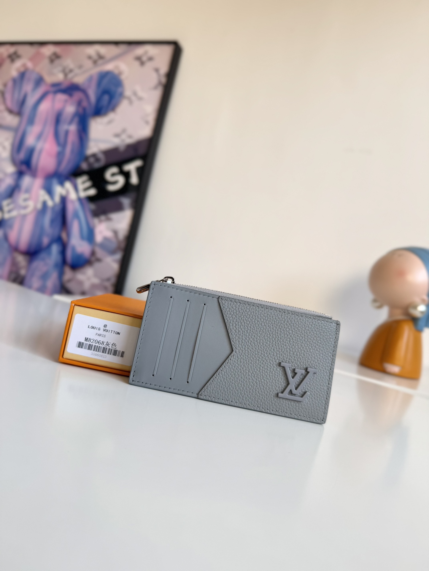 P360 M82068 Gray Tailored from Louis Vuitton's iconic Taiga leather, the Coin Card Holder has a sleek, clean look and is ideal for securely storing loose change and banknotes. Inside, there are multiple credit card slots and bill compartments, plus an additional zippered coin pocket.