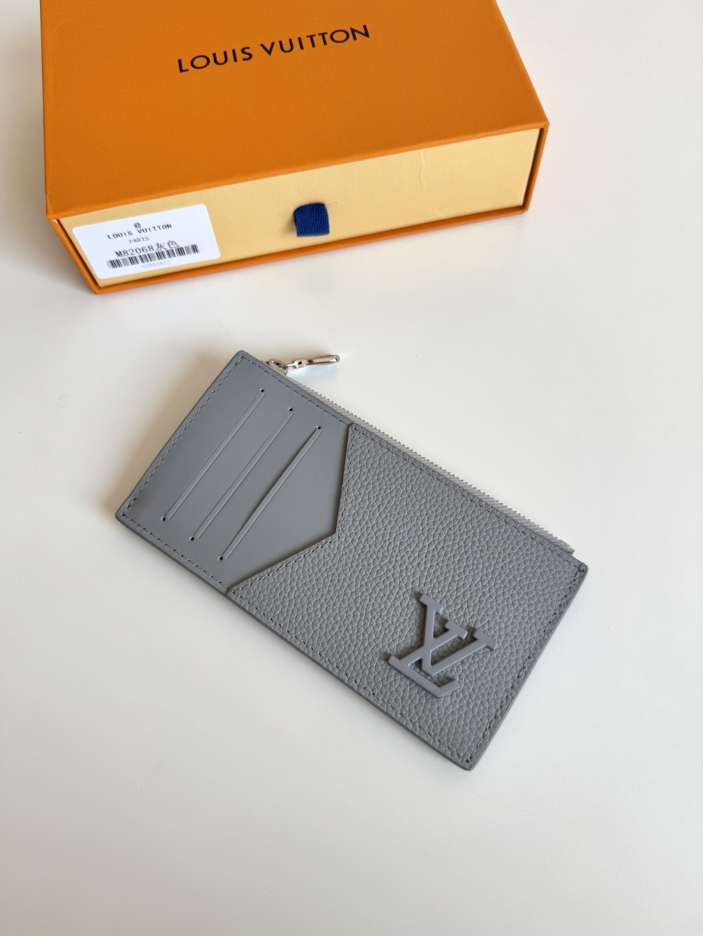 P360 M82068 Gray Tailored from Louis Vuitton's iconic Taiga leather, the Coin Card Holder has a sleek, clean look and is ideal for securely storing loose change and banknotes. Inside, there are multiple credit card slots and bill compartments, plus an additional zippered coin pocket.