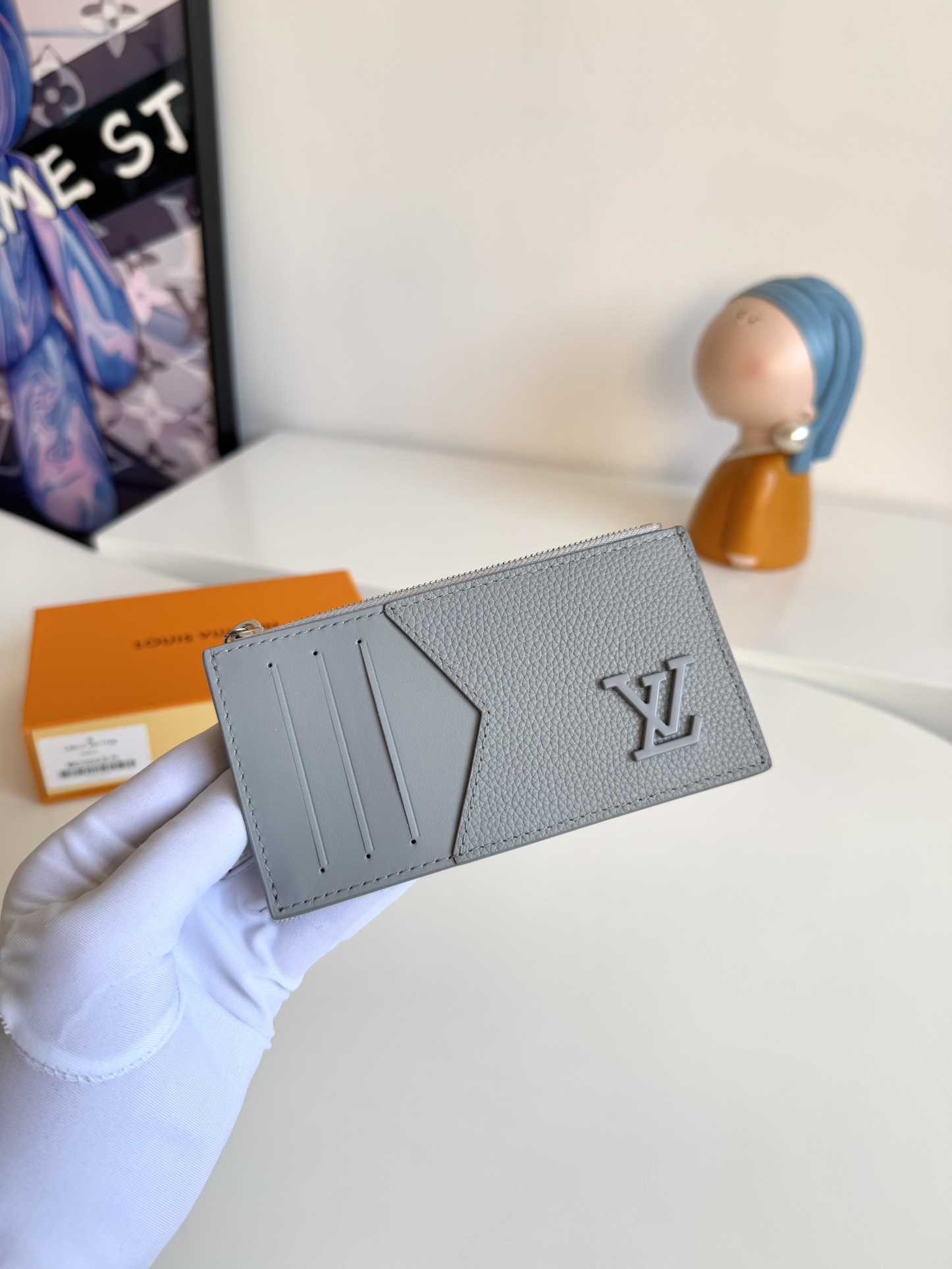 P360 M82068 Gray Tailored from Louis Vuitton's iconic Taiga leather, the Coin Card Holder has a sleek, clean look and is ideal for securely storing loose change and banknotes. Inside, there are multiple credit card slots and bill compartments, plus an additional zippered coin pocket.