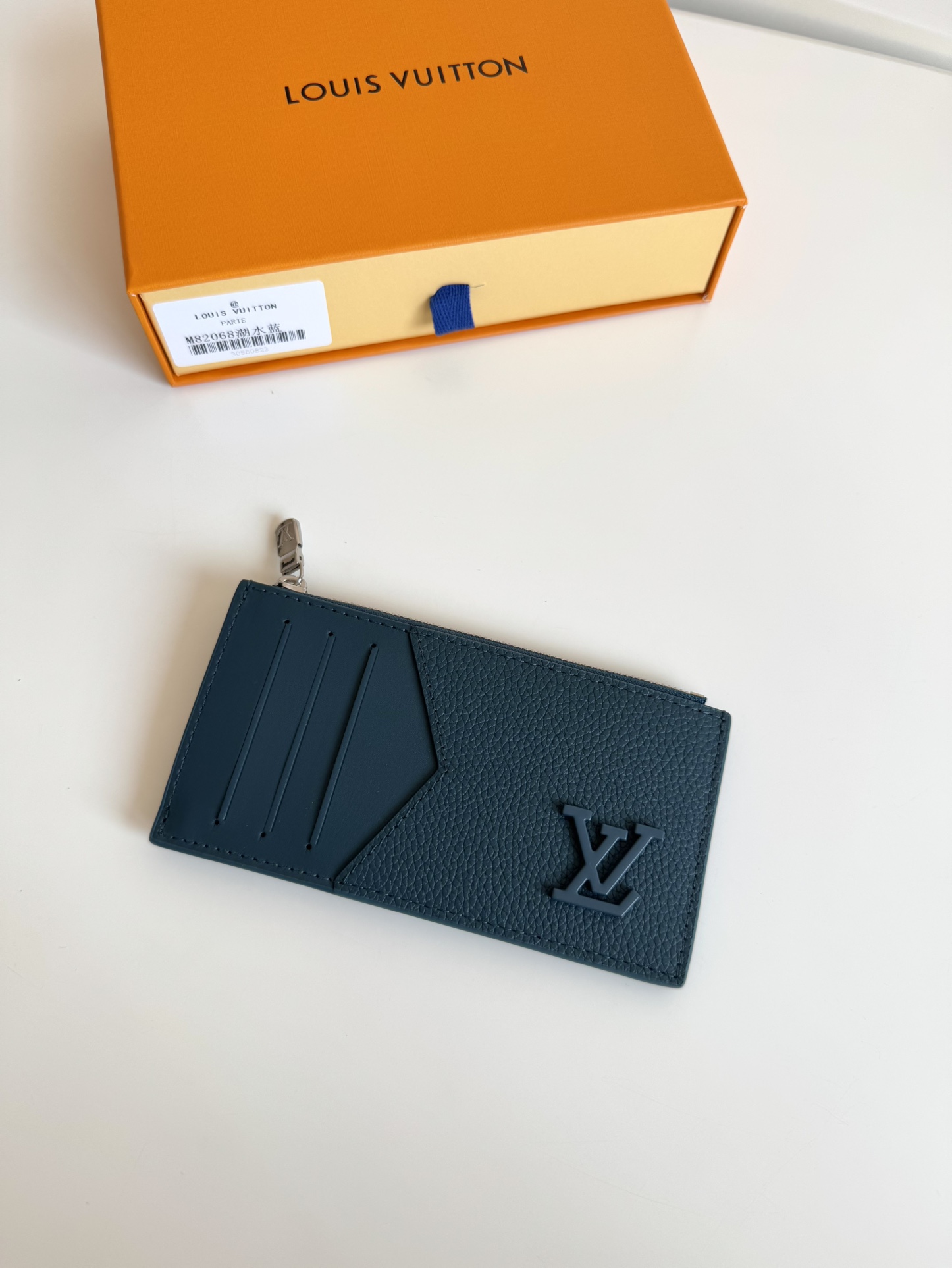 P360 M82068 Lake Blue Tailored from Louis Vuitton's iconic Taiga leather, the Coin card holder has a slim, clean look and is ideal for securely storing loose change and banknotes. Inside, there are multiple credit card slots and bill compartments, plus an additional zippered coin pocket.