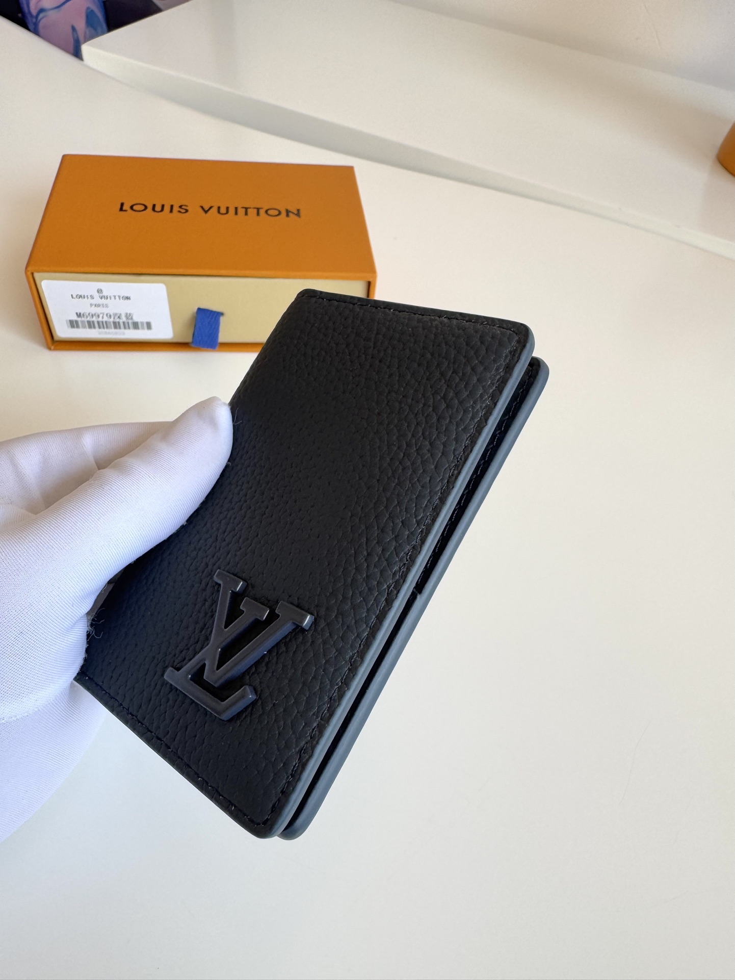 P280 M69979Negro Nuevo LV Aerogram Pocket Money ClipLa piel de vacuno seleccionada es tan suave como el membrete de una antigua aerolíneaLas letras LV metálicas subrayan la identidad de la marcaCon compartimentos y ranuras para tarjetas, es una fusión de elegancia y funcionalidad que puede combinarse con cualquiera de los bolsos de la colección Aerogram de LVMedidas: 11 x 8 cm.