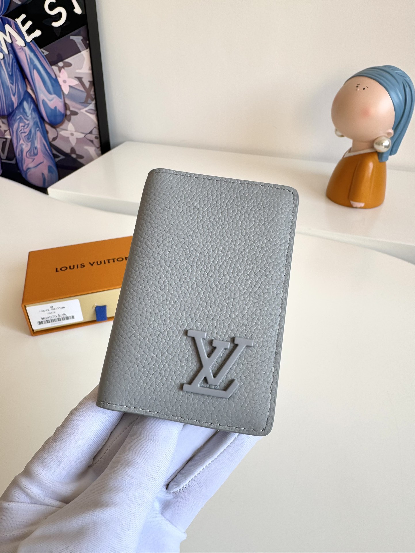 P280 M69979 Grey New LV Aerogram Pocket Money Clip Le cuir de vachette sélectionné est aussi doux qu'un vieux papier à en-tête de compagnie aérienne Les lettres LV en métal soulignent l'identité de la marque Avec des compartiments et des fentes pour cartes pour une fusion de l'élégance et de la fonctionnalité Peut être porté avec n'importe quel sac à main LV Aerogram Dimensions : 11 x 8 cm.