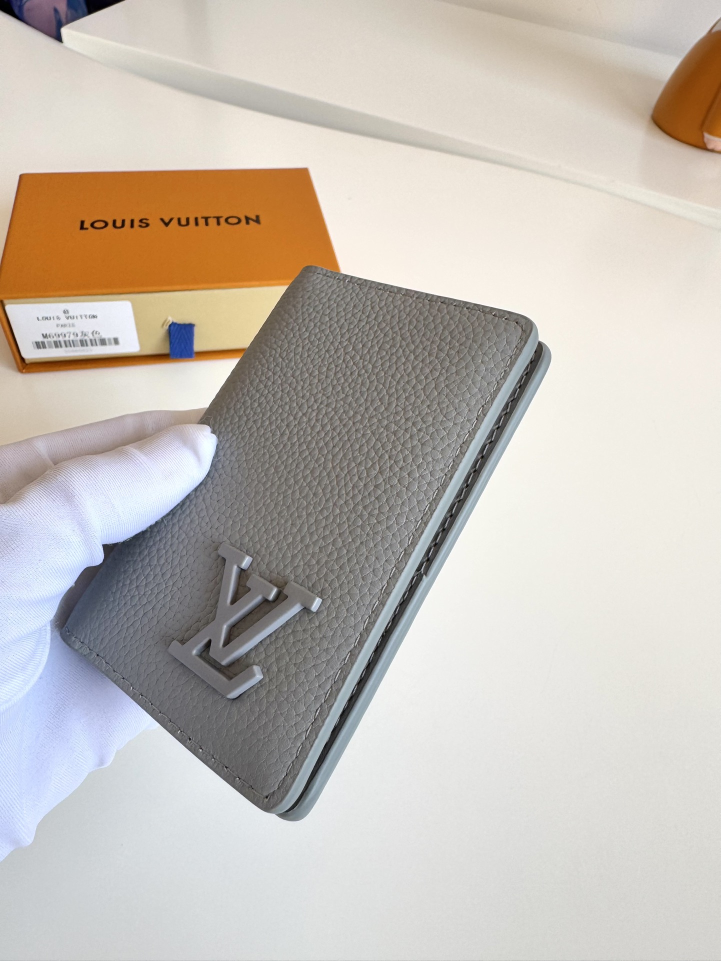 P280 M69979 Grey New LV Aerogram Pocket Money Clip Le cuir de vachette sélectionné est aussi doux qu'un vieux papier à en-tête de compagnie aérienne Les lettres LV en métal soulignent l'identité de la marque Avec des compartiments et des fentes pour cartes pour une fusion de l'élégance et de la fonctionnalité Peut être porté avec n'importe quel sac à main LV Aerogram Dimensions : 11 x 8 cm.