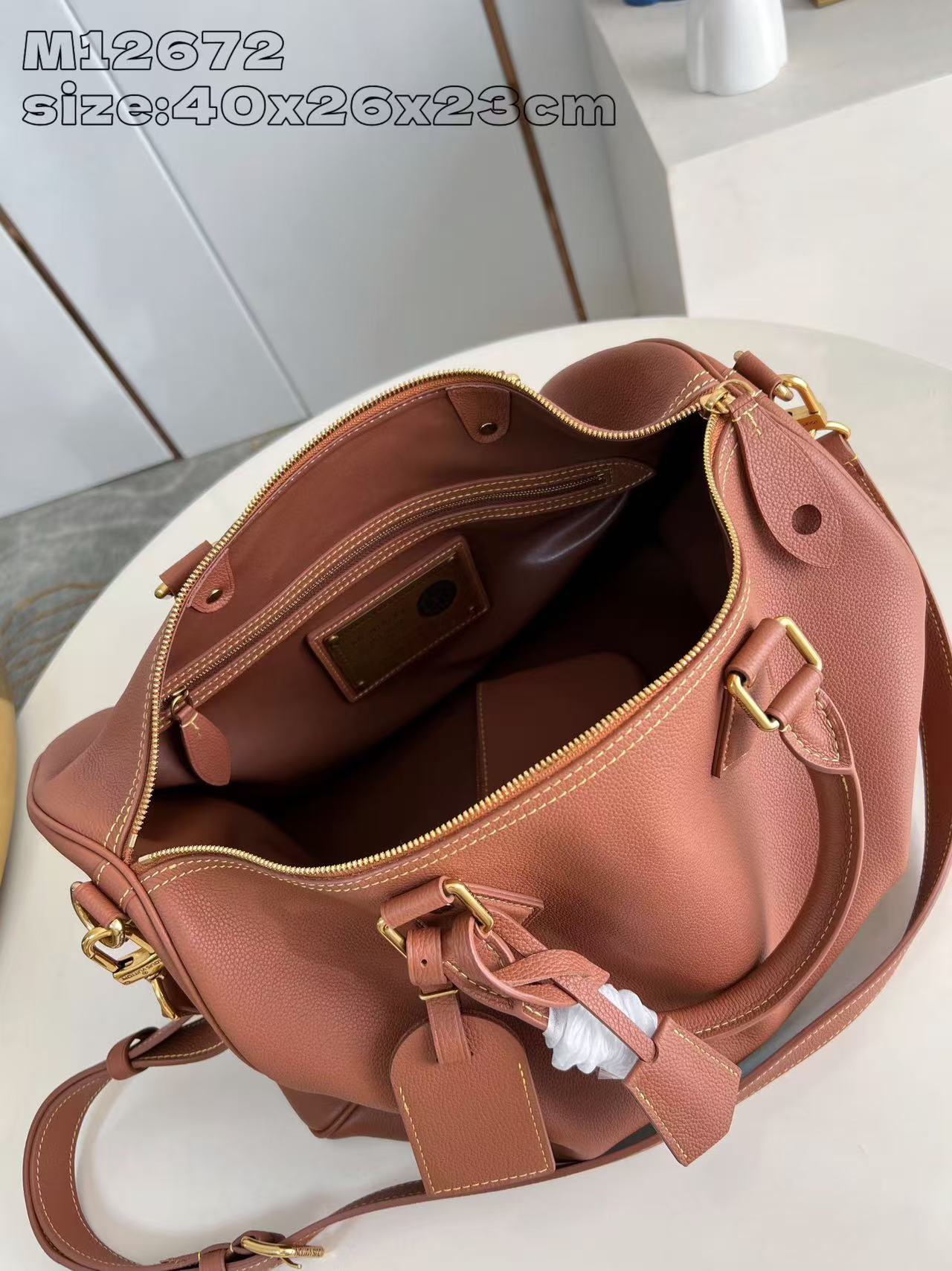 P2100 M12672 Marrón Este lujoso bolso Speedy Bandoulière 40 está confeccionado en piel de ternero ultrasuave y cuenta con un rico forro de piel de cordero de color coñac Incluye una bolsa de piel desmontable Dos asas superiores enrolladas de piel y una correa para el hombro desmontable y ajustable Para unas opciones de transporte versátiles Tamaño: 40x26x23cm